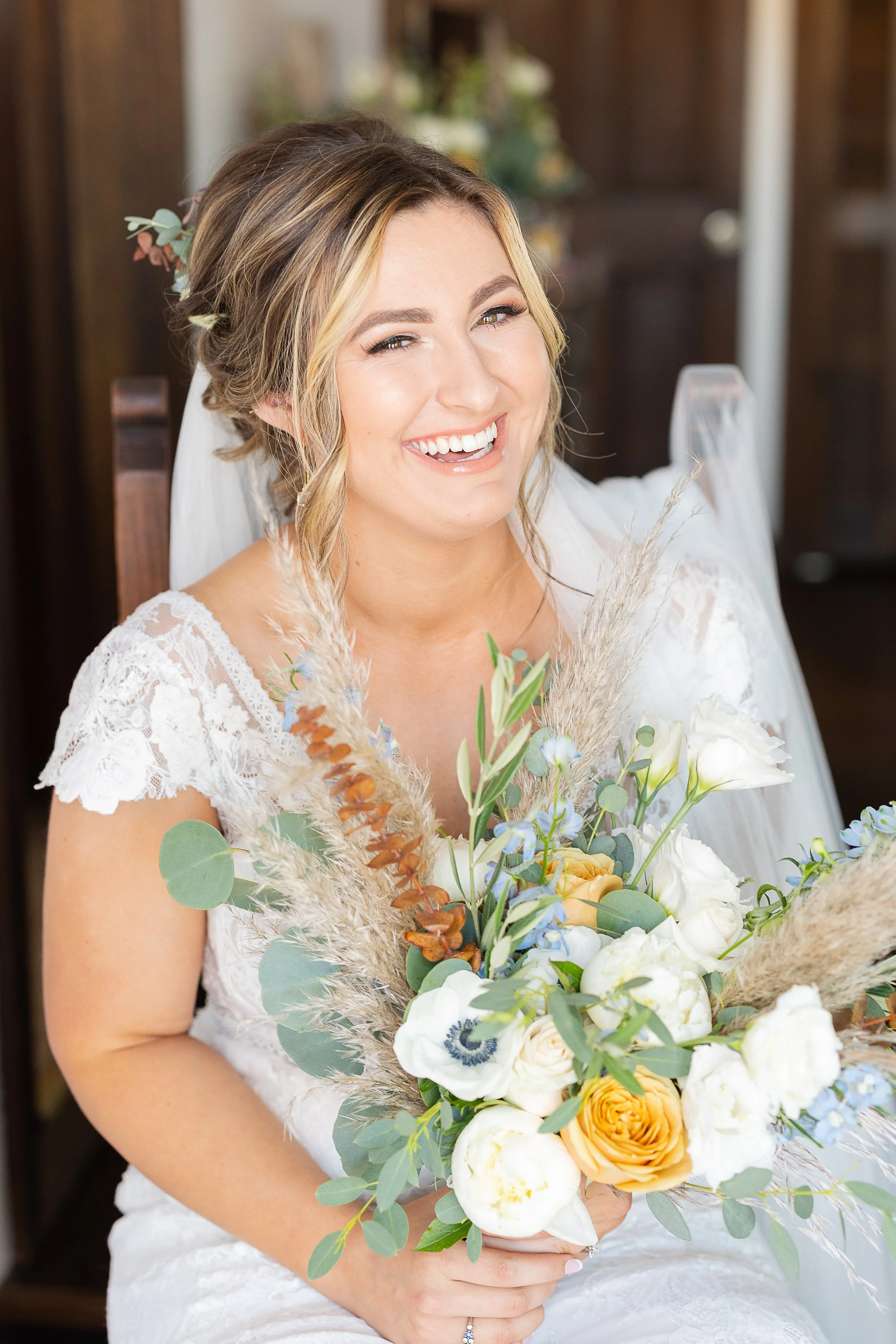 bride laughing while holding bridal bouquet made of anemones, toffee roses, eucalyptus, and pampas grass, sonora ca