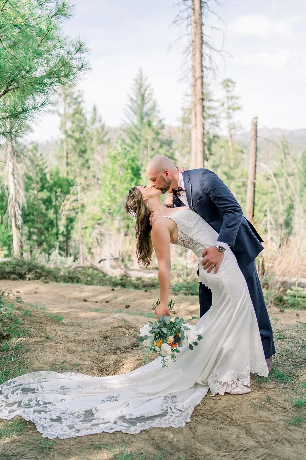 Bride and groom kissing while she holds her orange, white, and blue bridal bouquet, sonora florist