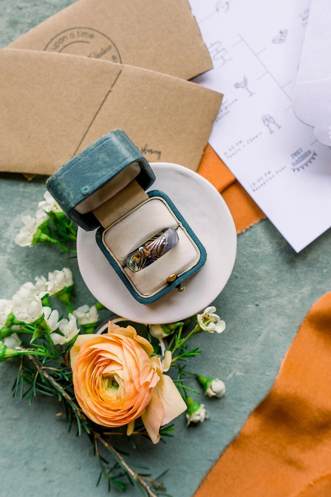 Wedding ring in box with orange ranunculus and wax flower around it, Sincerely sonora florist