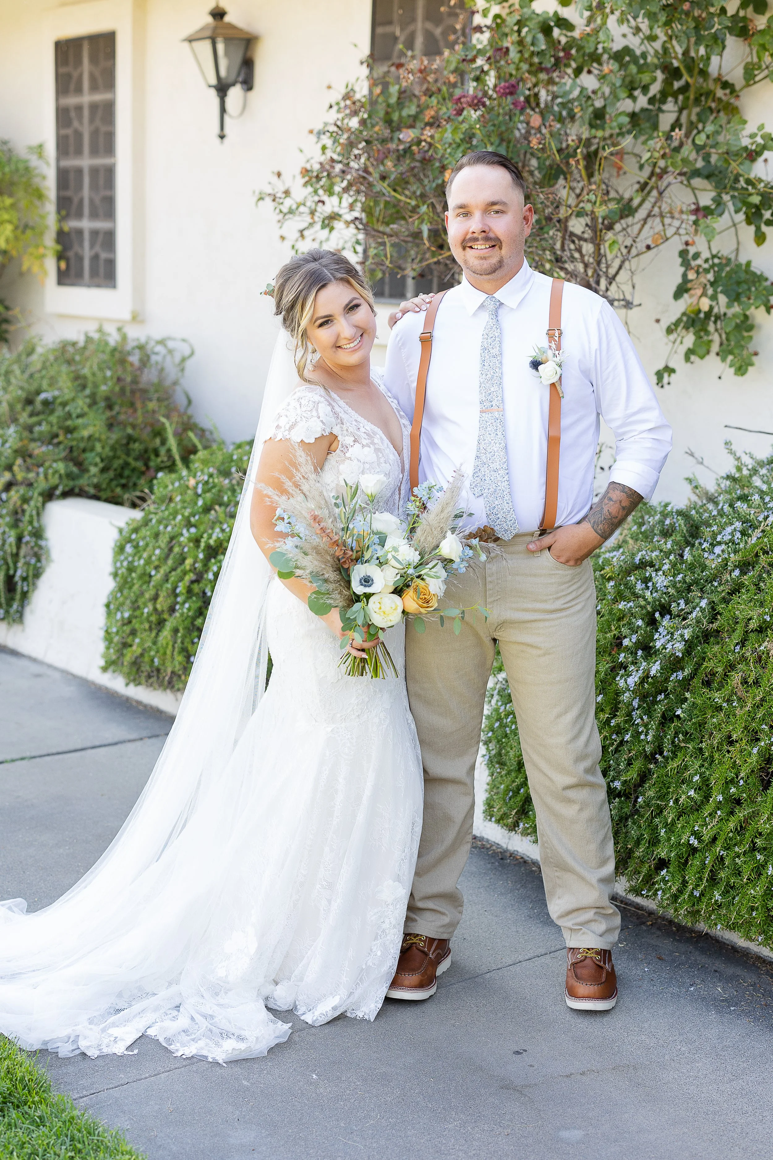 Bride and groom smiling wearing all white and tan while holding bridal bouquet, sonora florist