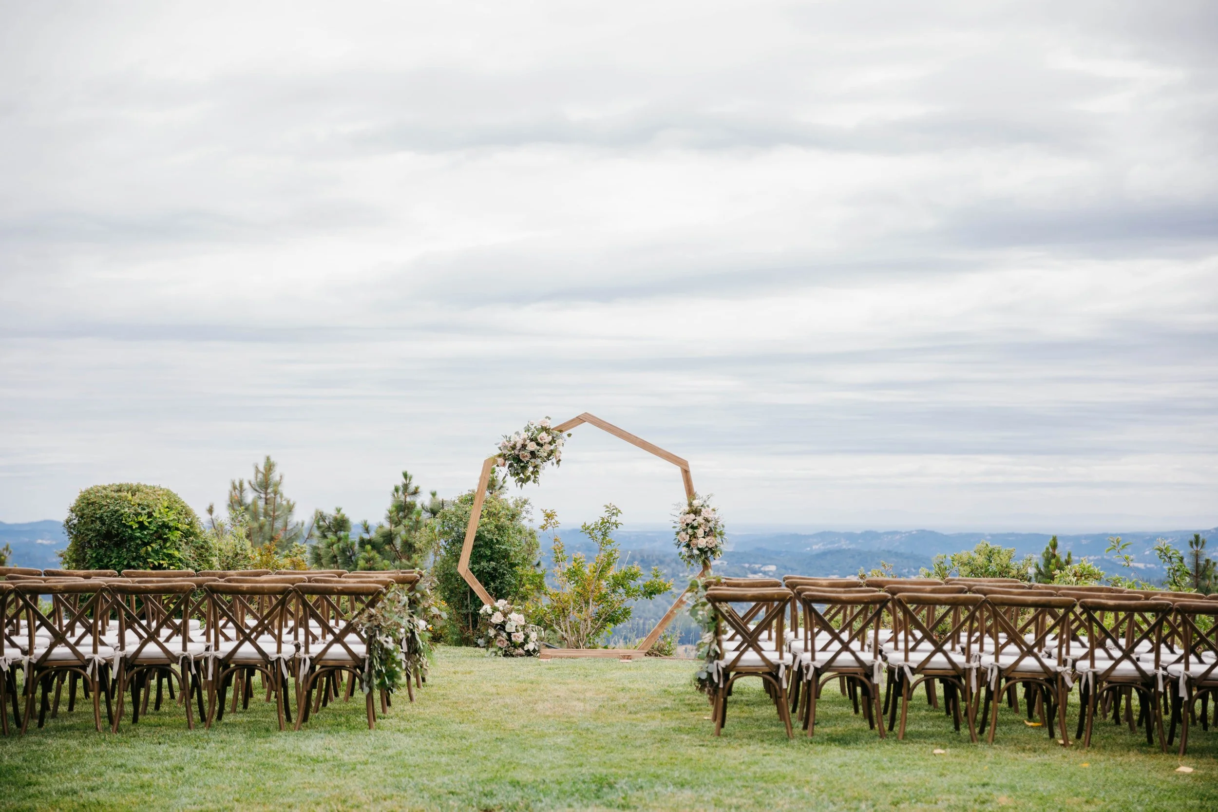 long shot of the arch at the end of the aisle with three clusters of flowers on it, sonora florist
