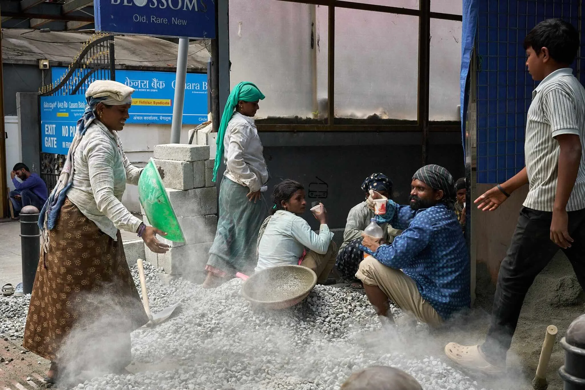 Jerzy Jaworek, Street and Travel Photography, India, Delhi. People gathered at a roadside construction site, mixing or handling gravel or stones.