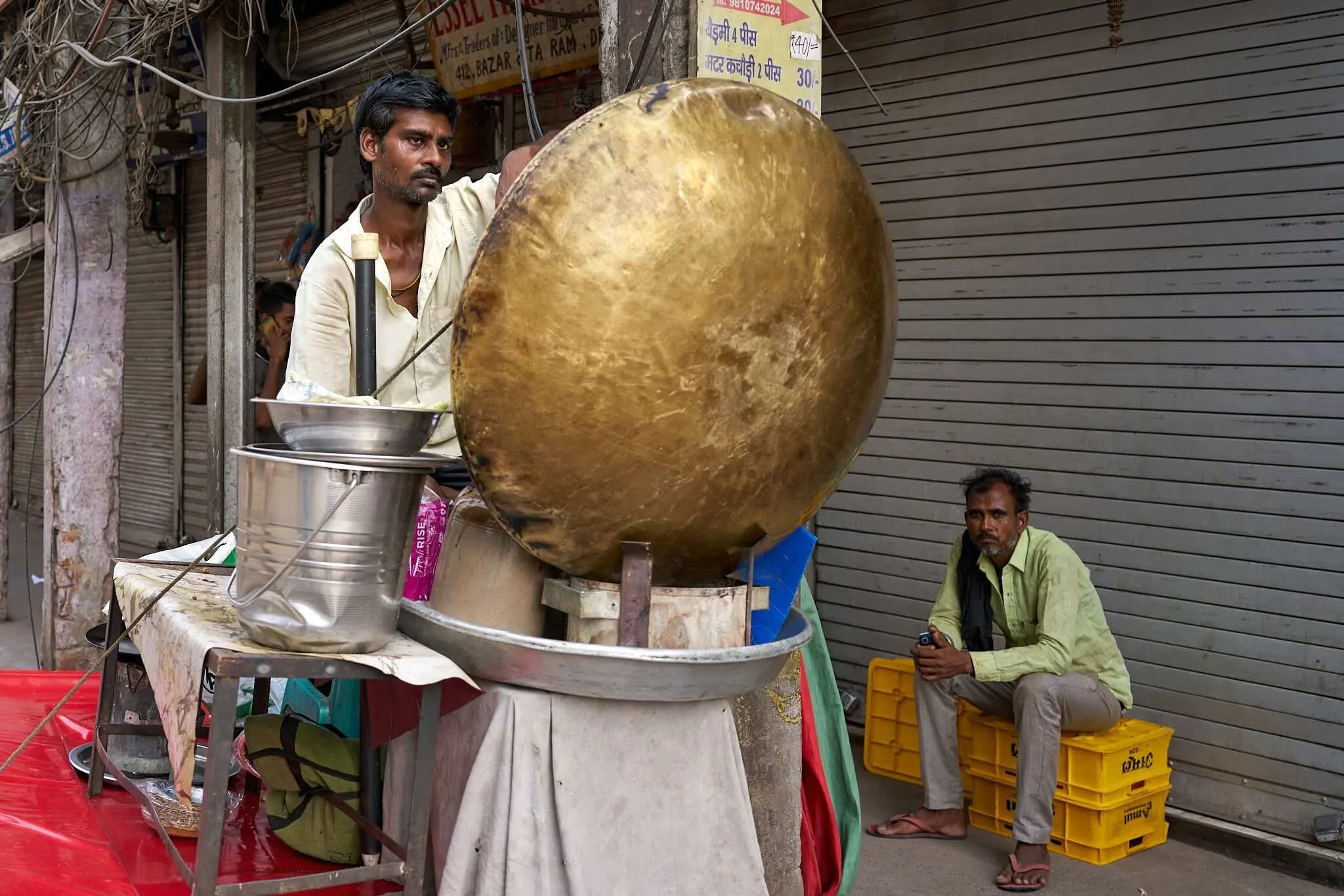 Jerzy Jaworek, Street and Travel Photography, India, Delhi. A street market scene with two men, one standing and the other sitting, near a cotton candy machine. 