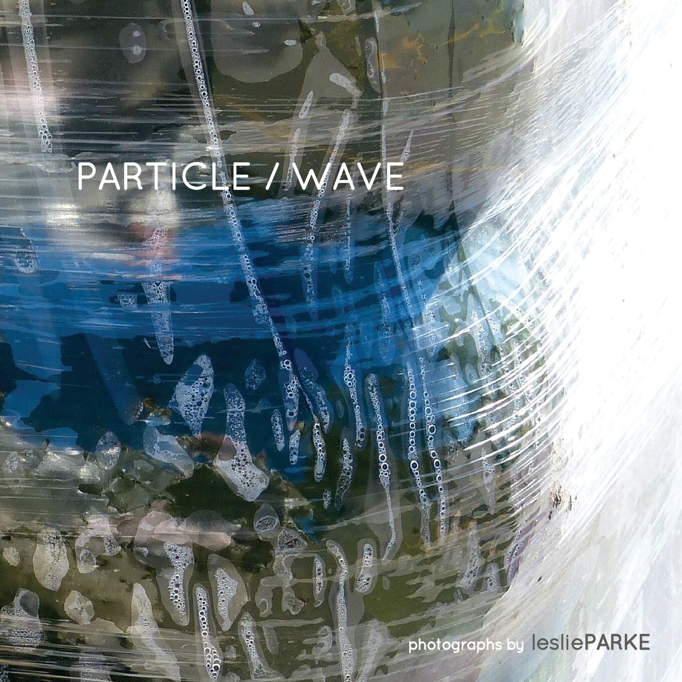 Abstract artwork titled "Particle / Wave" by Leslie Parke, featuring textured patterns and reflections on a glossy surface.