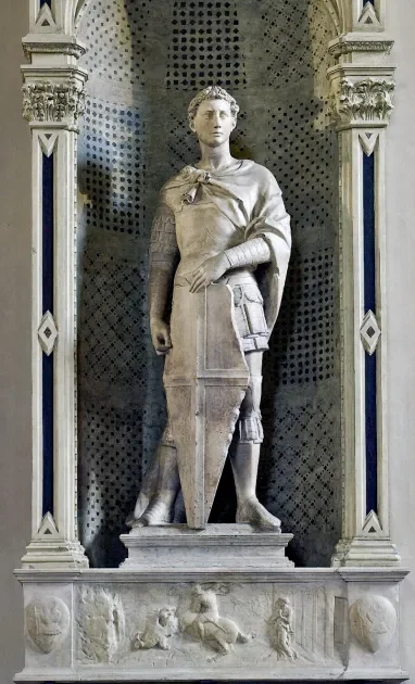 Donatello’s Saint George, c. 1415–17, showing the armored young saint standing upright with a large shield in a Gothic niche, poised and alert.