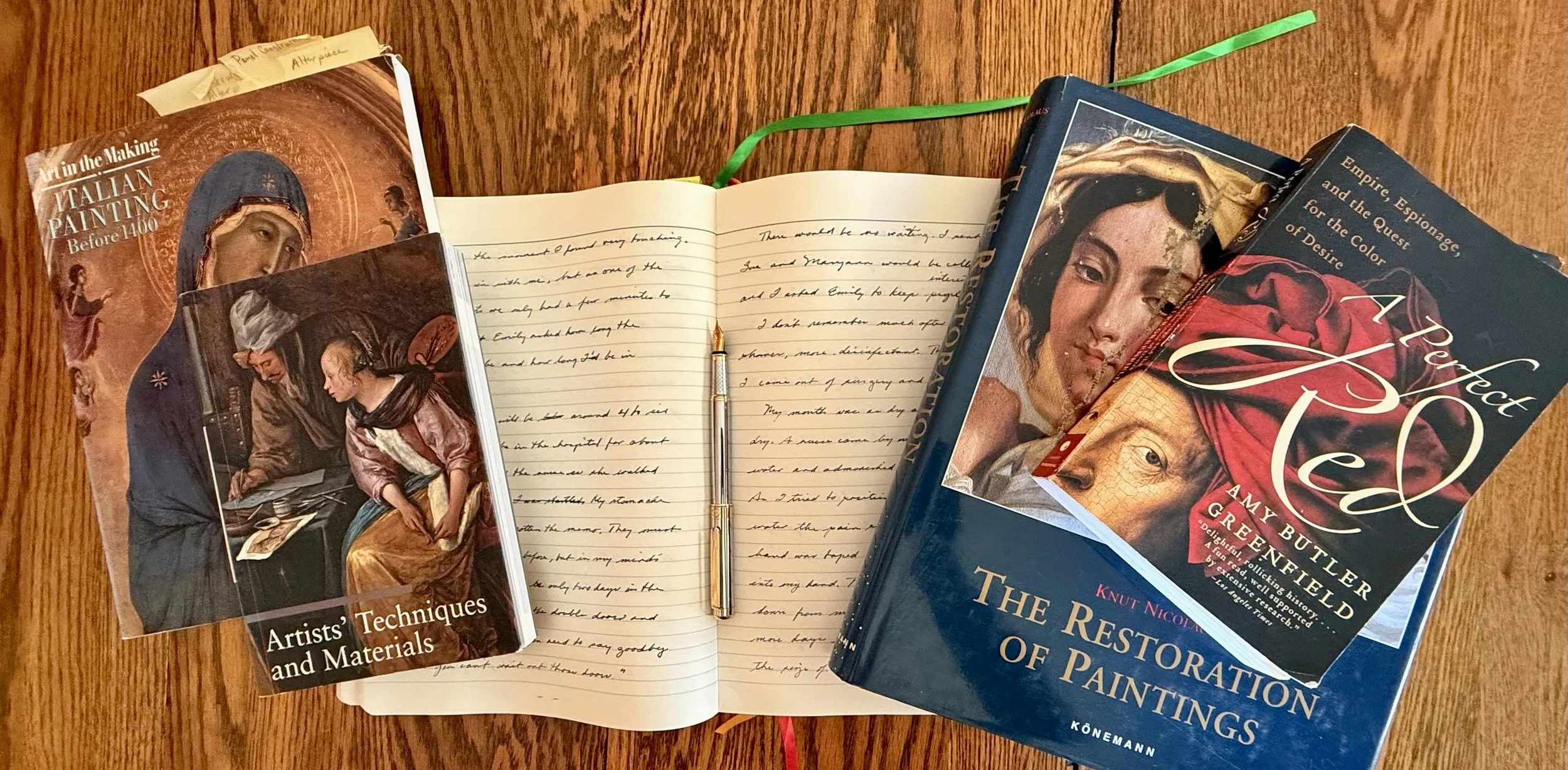 Wooden dest with notebook, fountain pen, 44 books on art history, Iralian Painting before 1400, painting restoration, the color red, and artists materials.