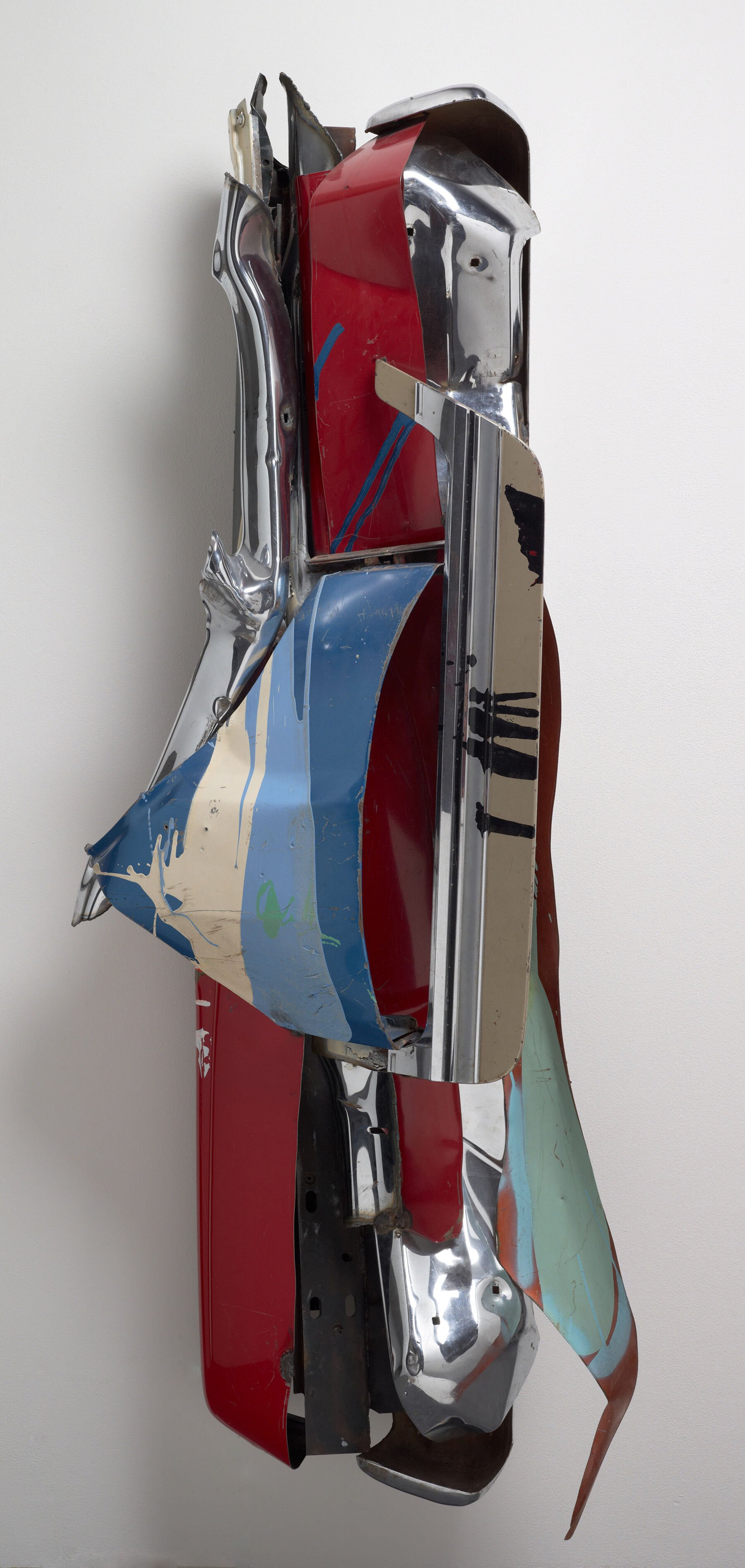 John Chamberlain’s Rare Meat (1977), a vertical wall sculpture assembled from crushed automobile parts in red, chrome, blue, and cream. Twisted metal panels create rhythmic movement and painterly color relationships.