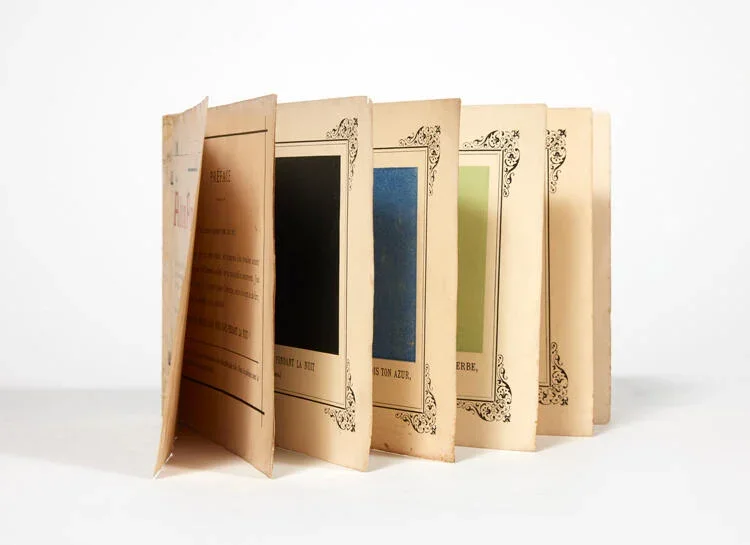 Open copy of Alphonse Allais’s Album primo-avrilesque, 1897, showing several colored monochrome pages including black, blue, and green.