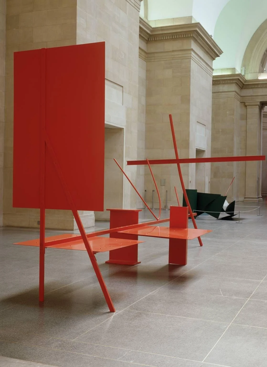Anthony Caro abstract steel sculpture in vivid red, balancing open planes and linear forms in a museum atrium with lyrical spatial movement and modernist clarity.