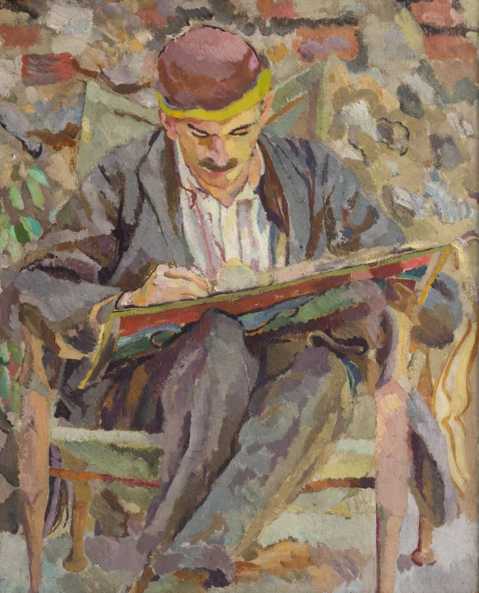 A portrait of Maynard Keynes by Duncan Grant, in colorful blotches of paint. Keynes sits in a chair writing on a lap desk.