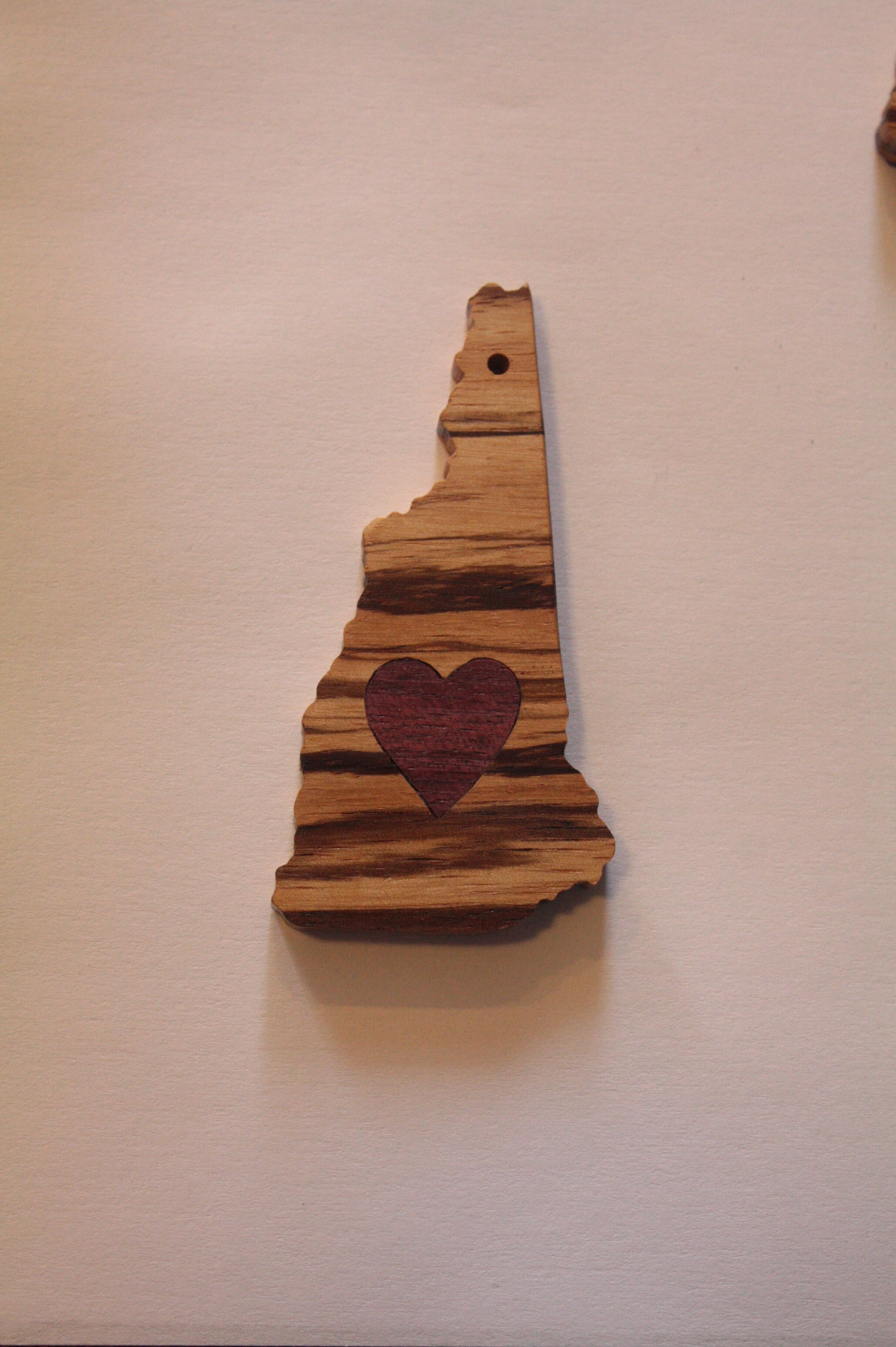 A key chain made from purple heart and zebra wood. It's funny how good the state of NH feels in your hand as a key chain. This item is available online!