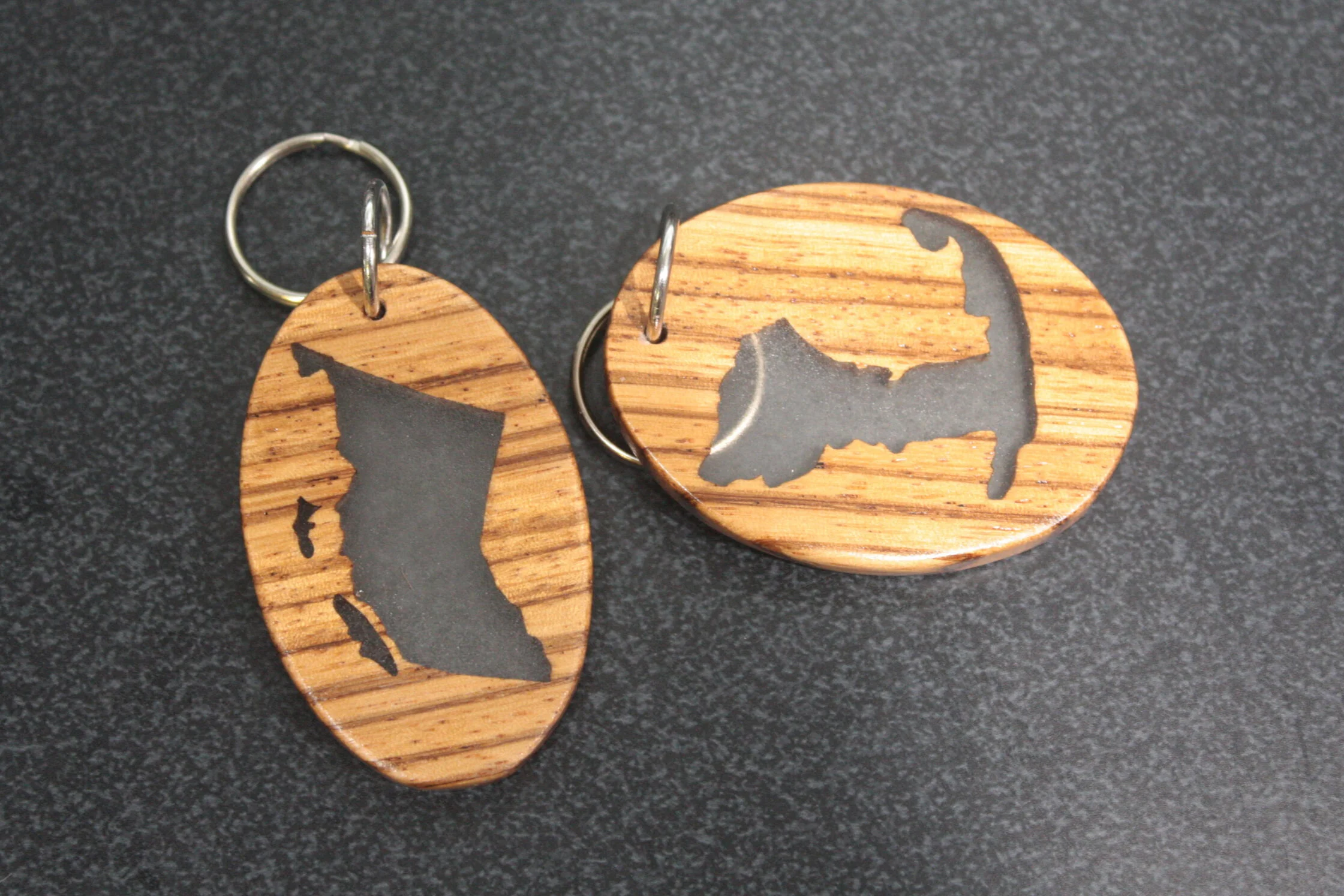These are custom made British Columbia and Cape Cod keychains. They are hand cut on the scroll saw and filled with clear resin for extra strength. I just love the way zebra wood looks on small stuff like this.