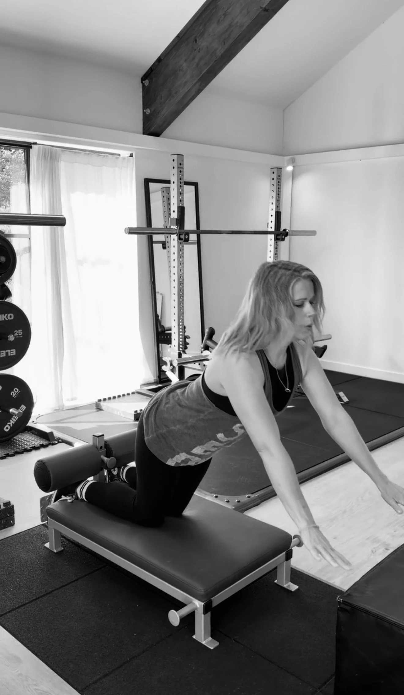 Black and white photo of a skateboard, foam roller, and a spinning disc in a gym or workout space.