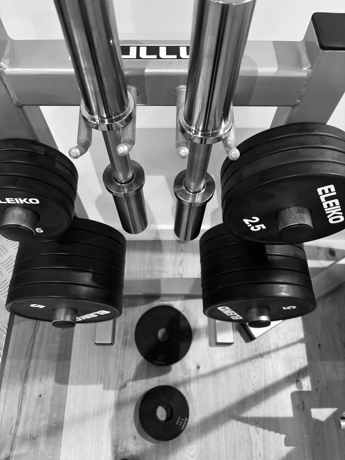 A set of dumbbells on a weight rack with weight plates nearby in a gym, viewed from above.