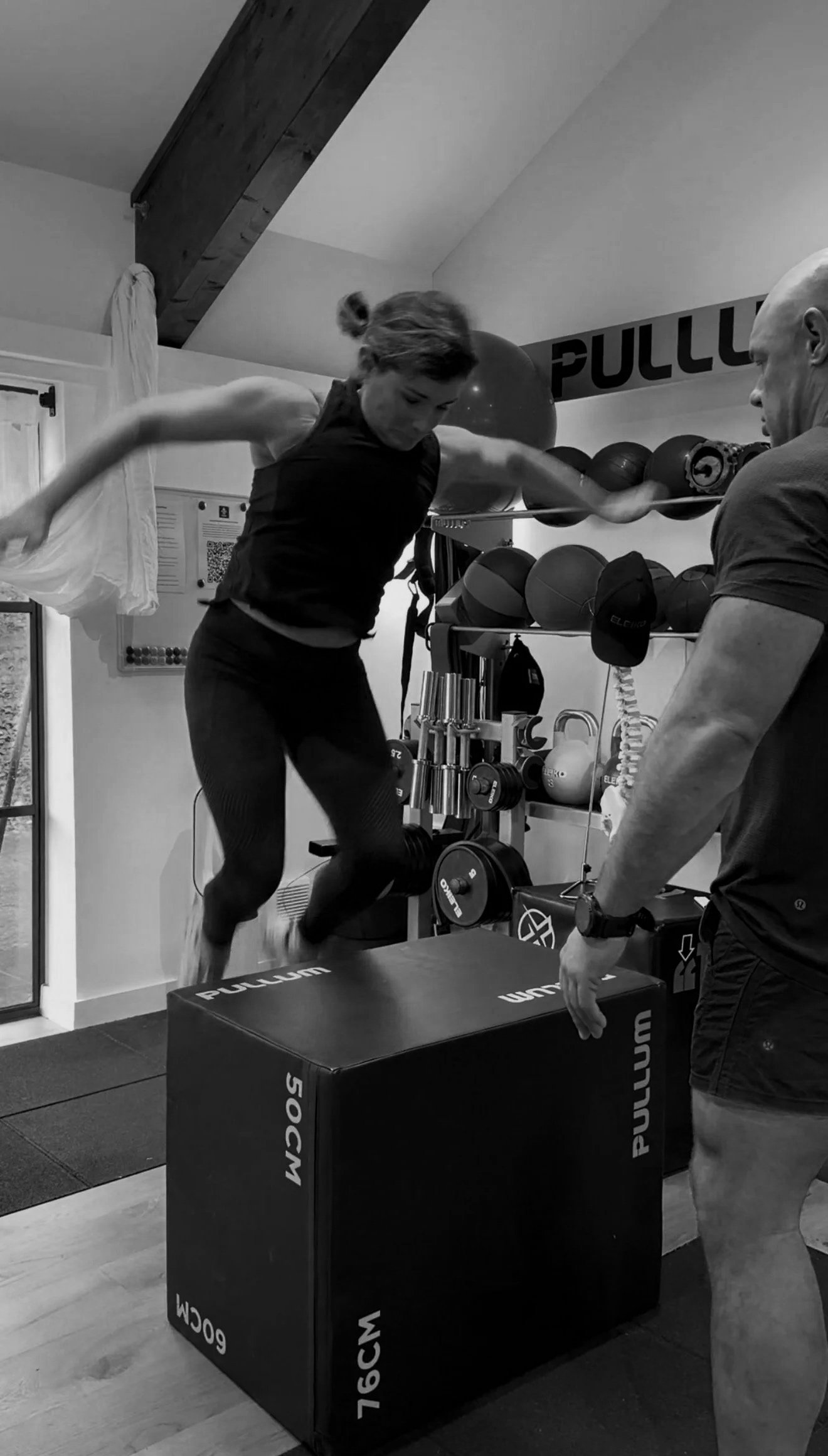 A person's hand gripping a textured barbell at a gym, with a weight plate labeled '20 KG' in the background.
