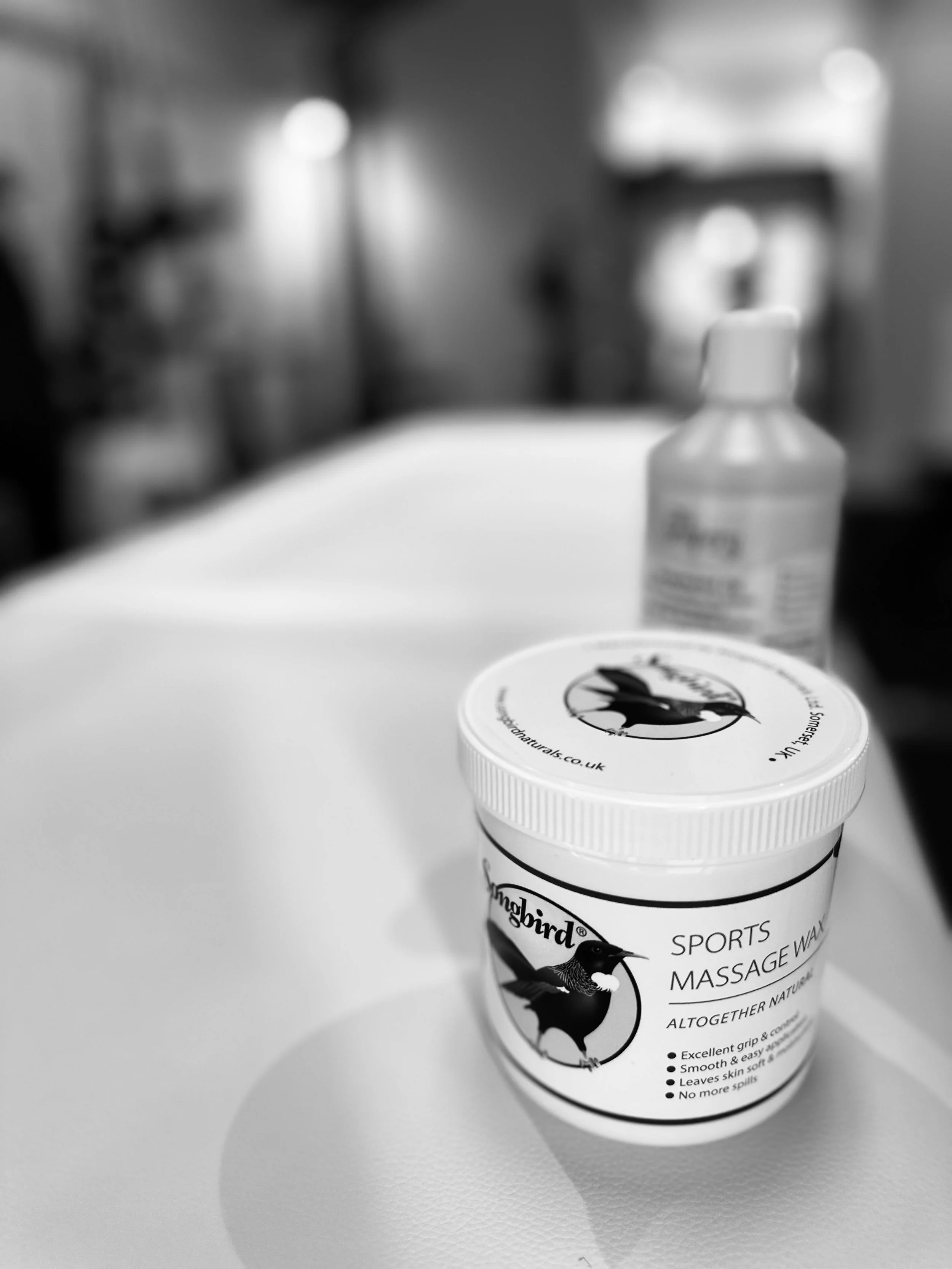 Massage table with a headrest and a small tray, in a room with wooden shelves and baskets.