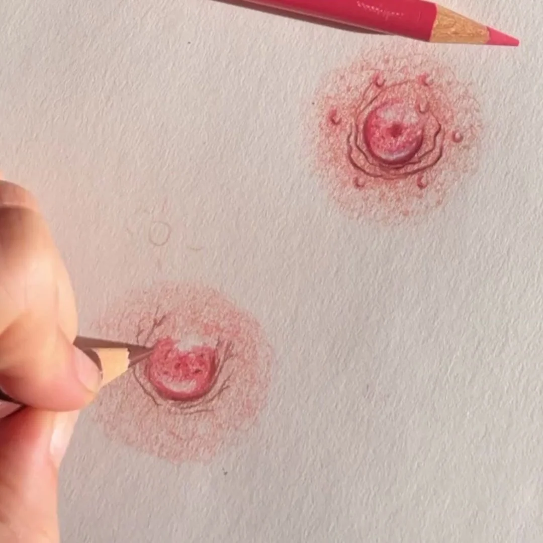 Artistic drawing of two smiling red peanuts with swirling lines and textured shading on white paper, with a hand using a colored pencil to add details.