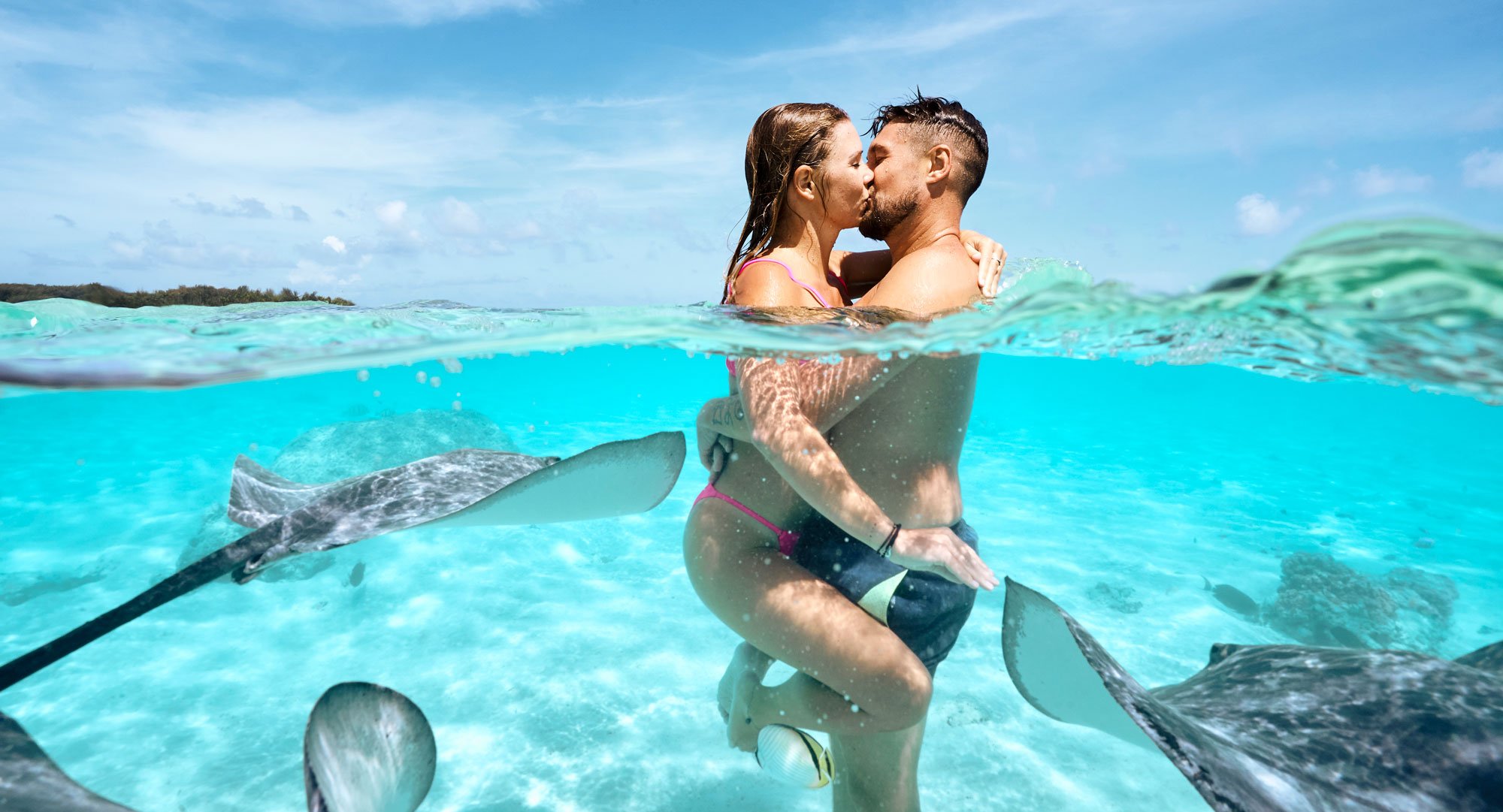 couple qui s'embrasse au milieu des raies à moorea