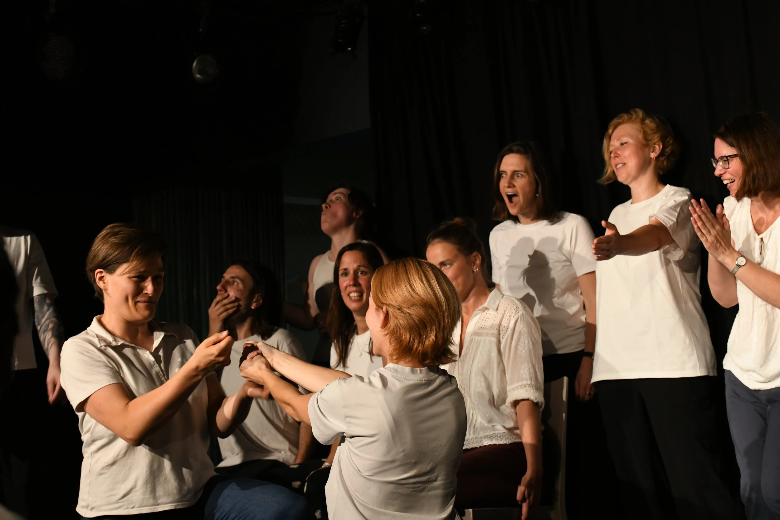 A group of women on stage celebrating, smiling, and holding hands during a performance or ceremony.