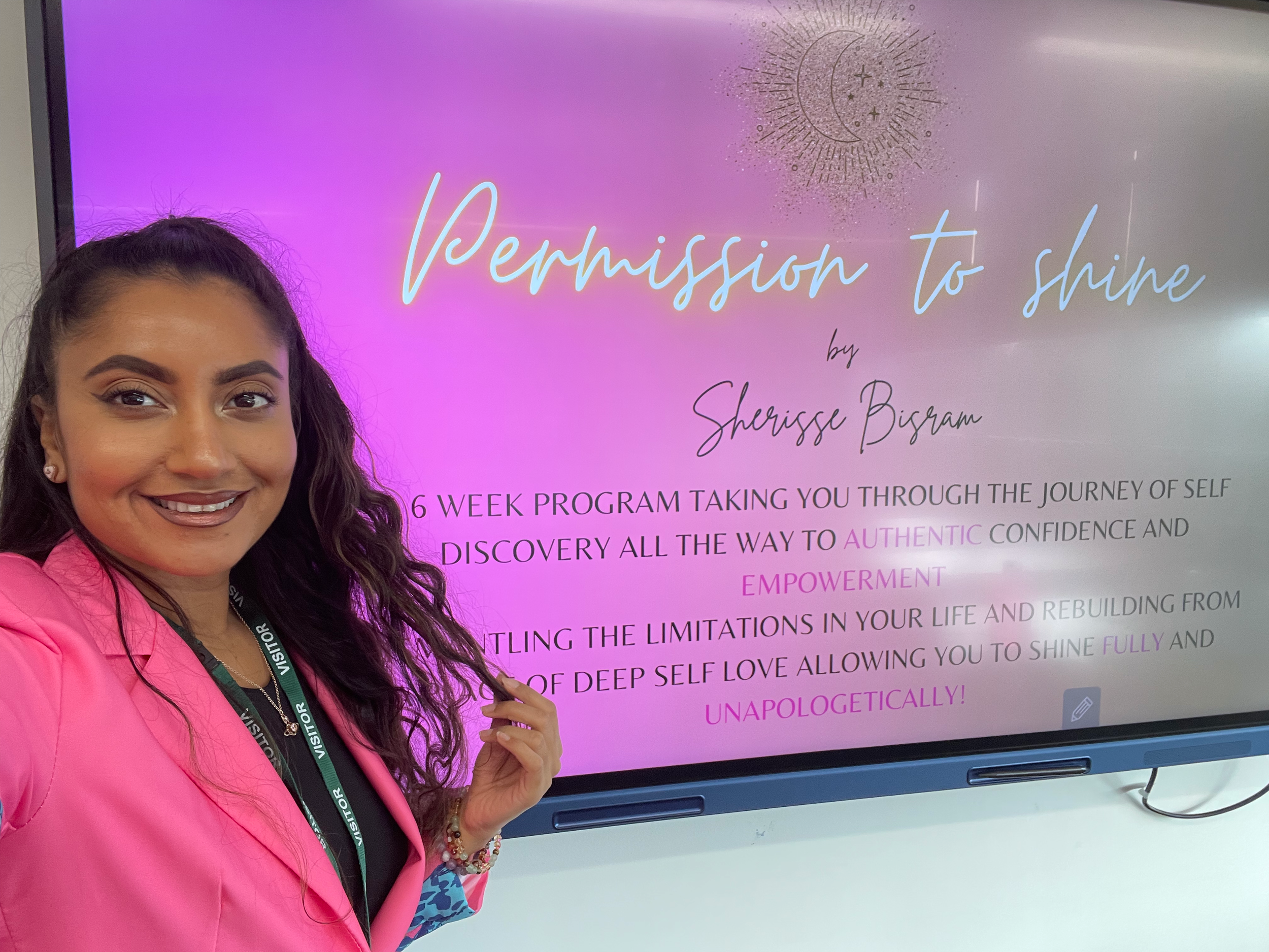 Smiling woman wearing a "visitor" lanyard standing in front of a presentation display with text about empowerment and personal journey."