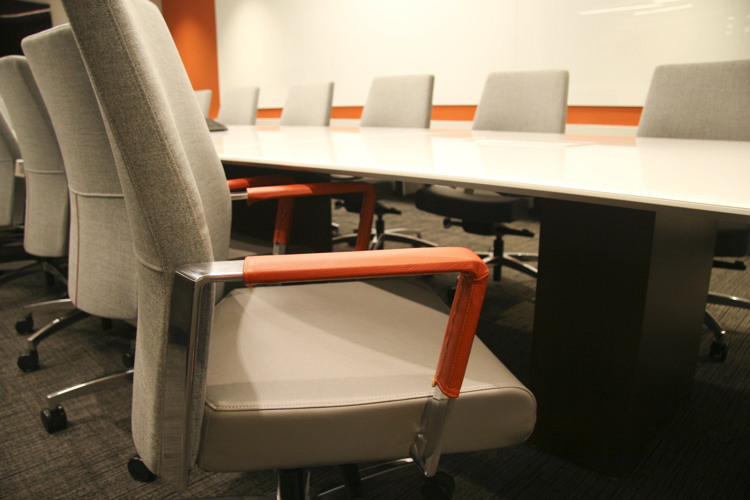 Modern conference room with gray chairs and white table, featuring orange accents.