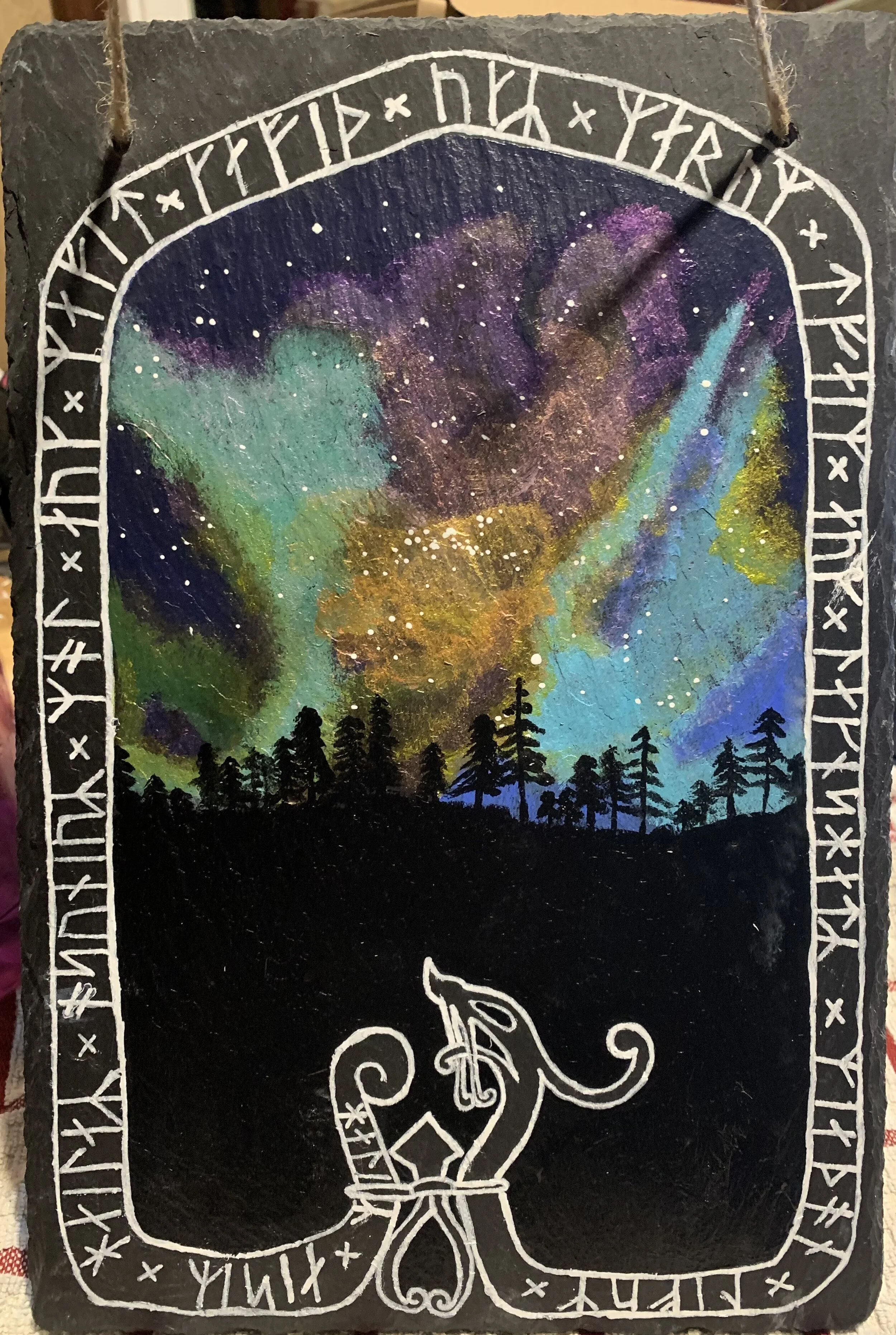A painting of a starry night sky with colorful nebulae over a silhouette of a forest, framed by runic symbols and a stylized horse figure at the bottom.