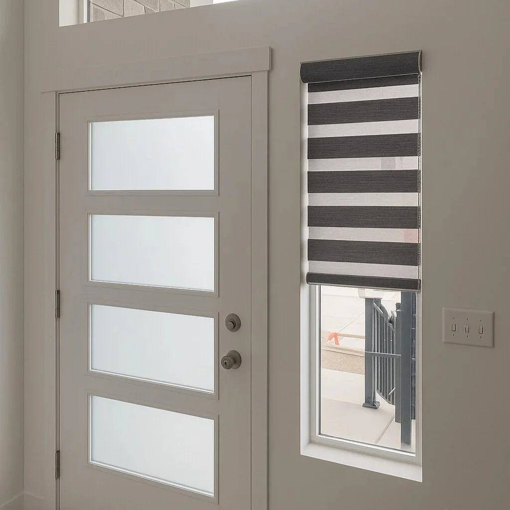 Interior view of a white door with four frosted glass panels and a modern stripe-patterned window blind on the right side, with partial outside view, white walls, and light-colored flooring.