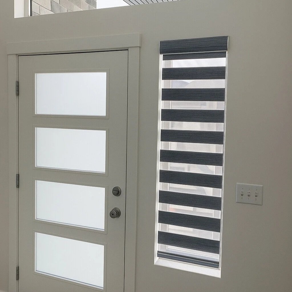 Interior view of a modern entryway with a white door featuring four frosted glass panels and a rectangular window with dark blinds to the right.