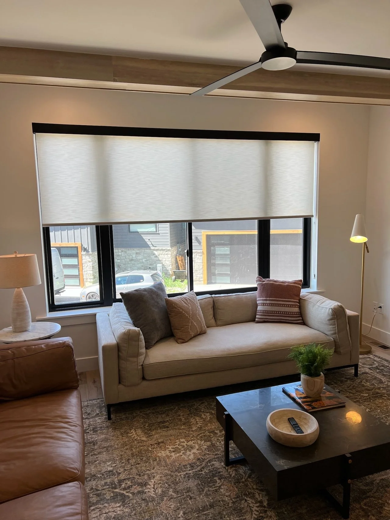 Living room with two sofas, a coffee table, window with blinds, and ceiling fan.
