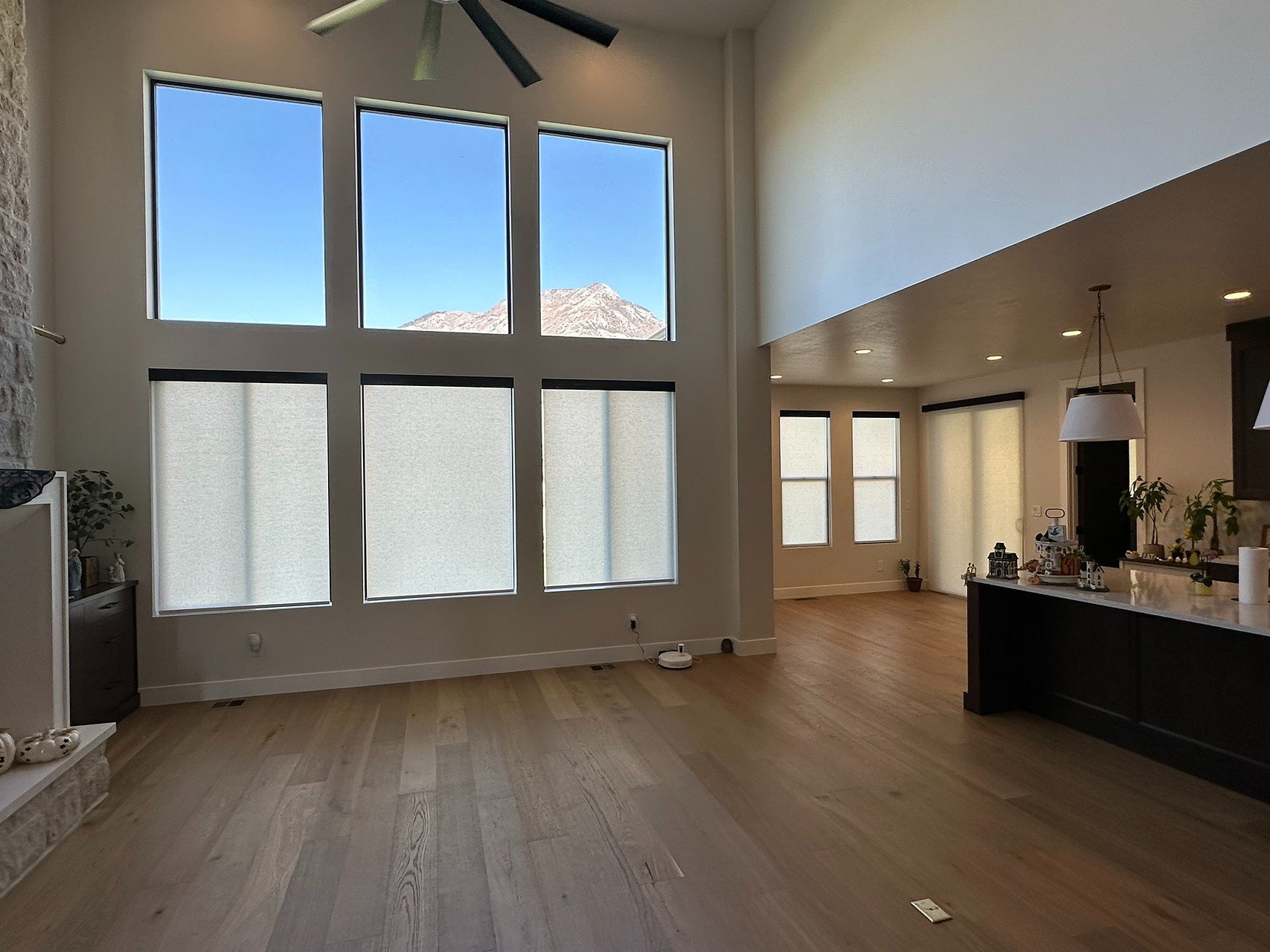 Living room with large floor-to-ceiling windows showing mountain view, wooden flooring, and a ceiling fan.