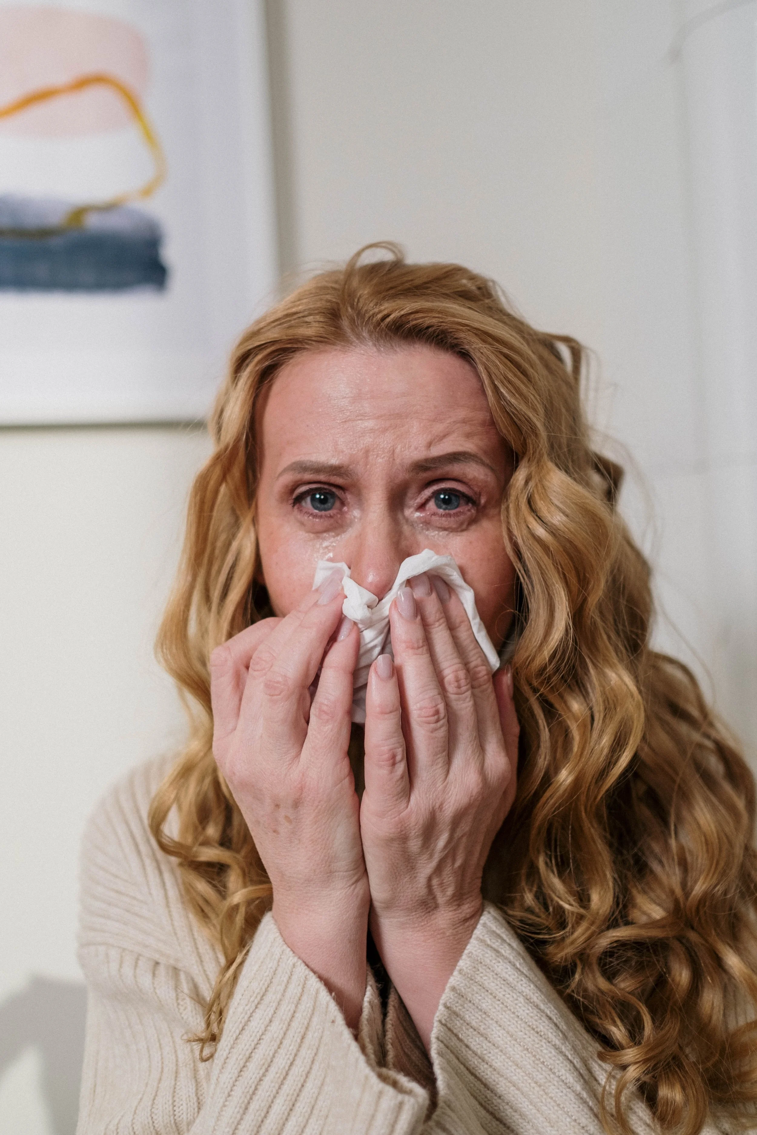 woman blowing her nose due to allergies