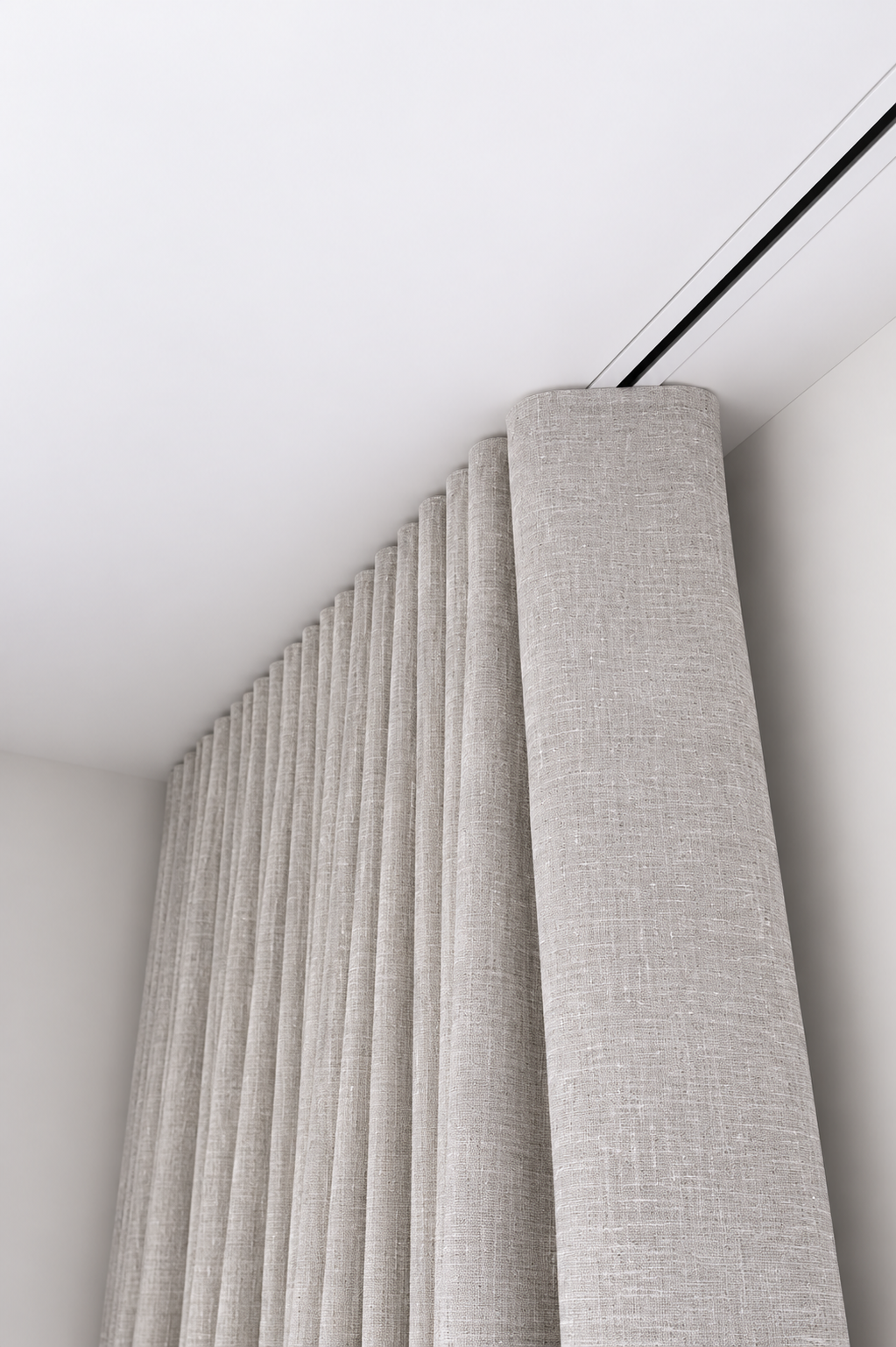 Close-up of grey fabric curtains hanging from a ceiling track in a modern room with white walls.