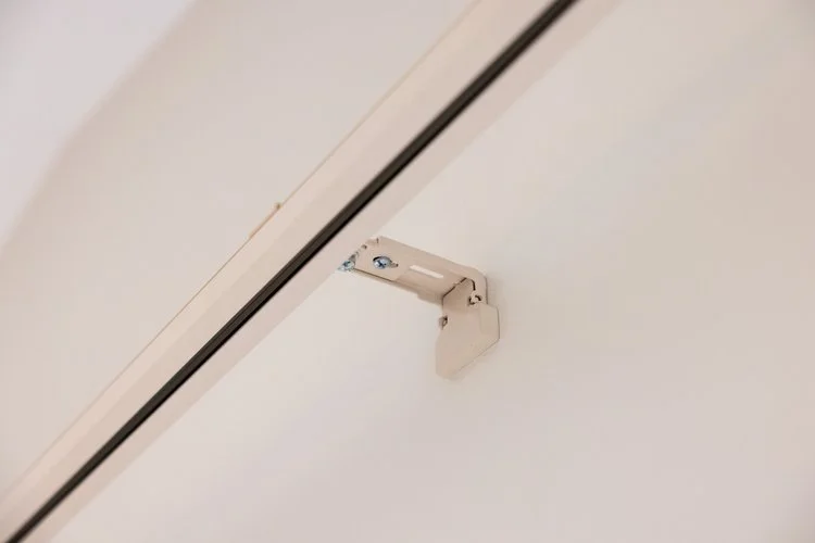 Close-up of a white curtain track bracket attached to the wall.