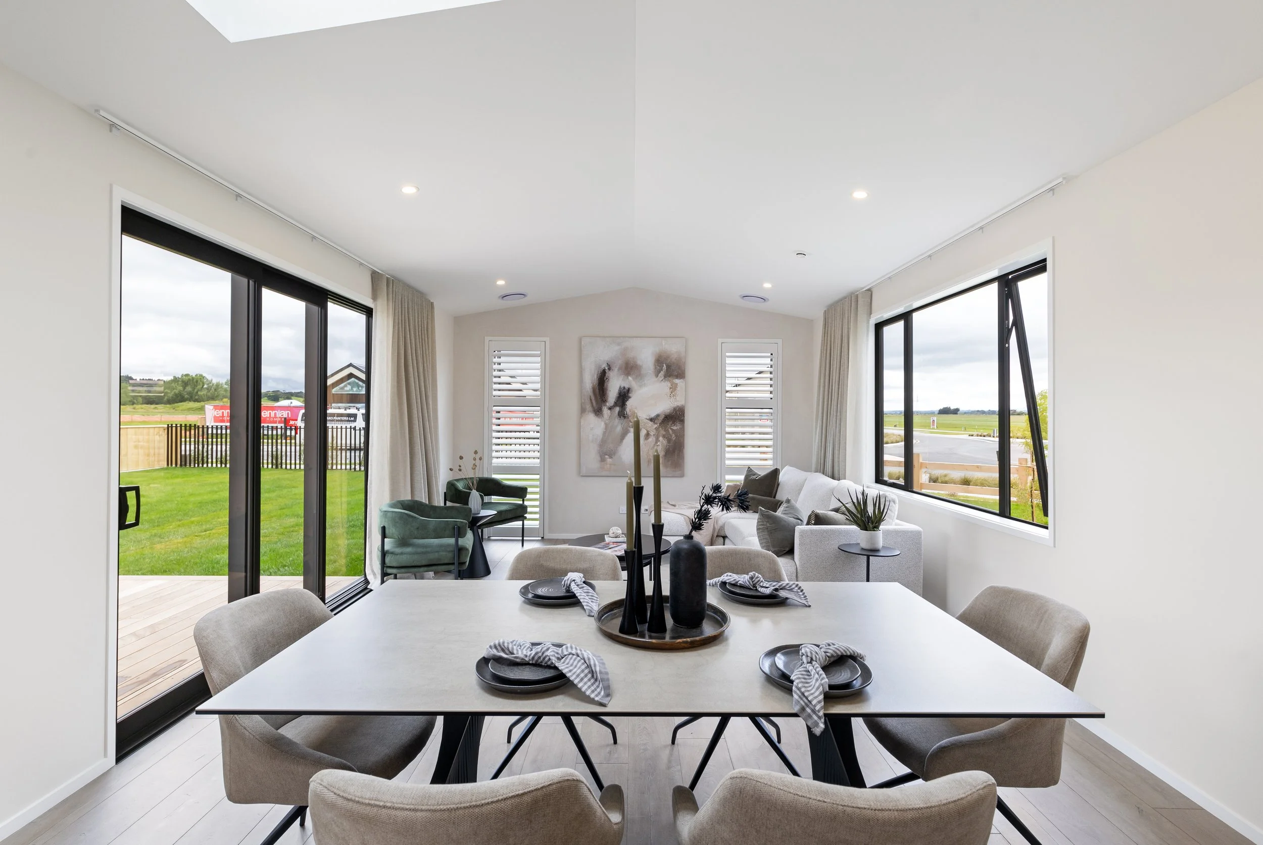 Bright open-concept living and dining area with large windows, modern furnishings, and green outdoor views.