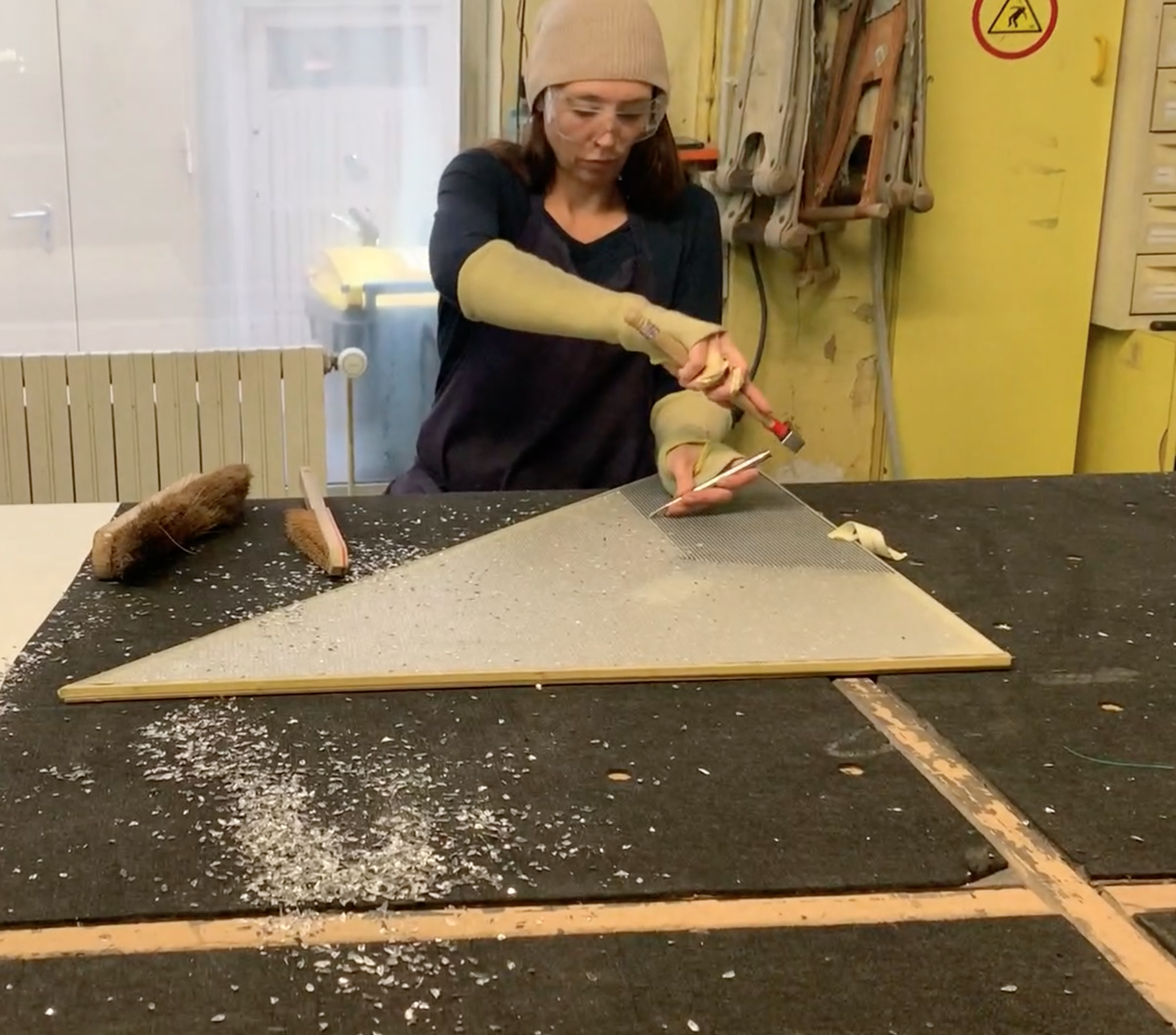 Parisian glass artisan hand-etching the back of a glass panel to create texture, and to prep for metal leaf backing.