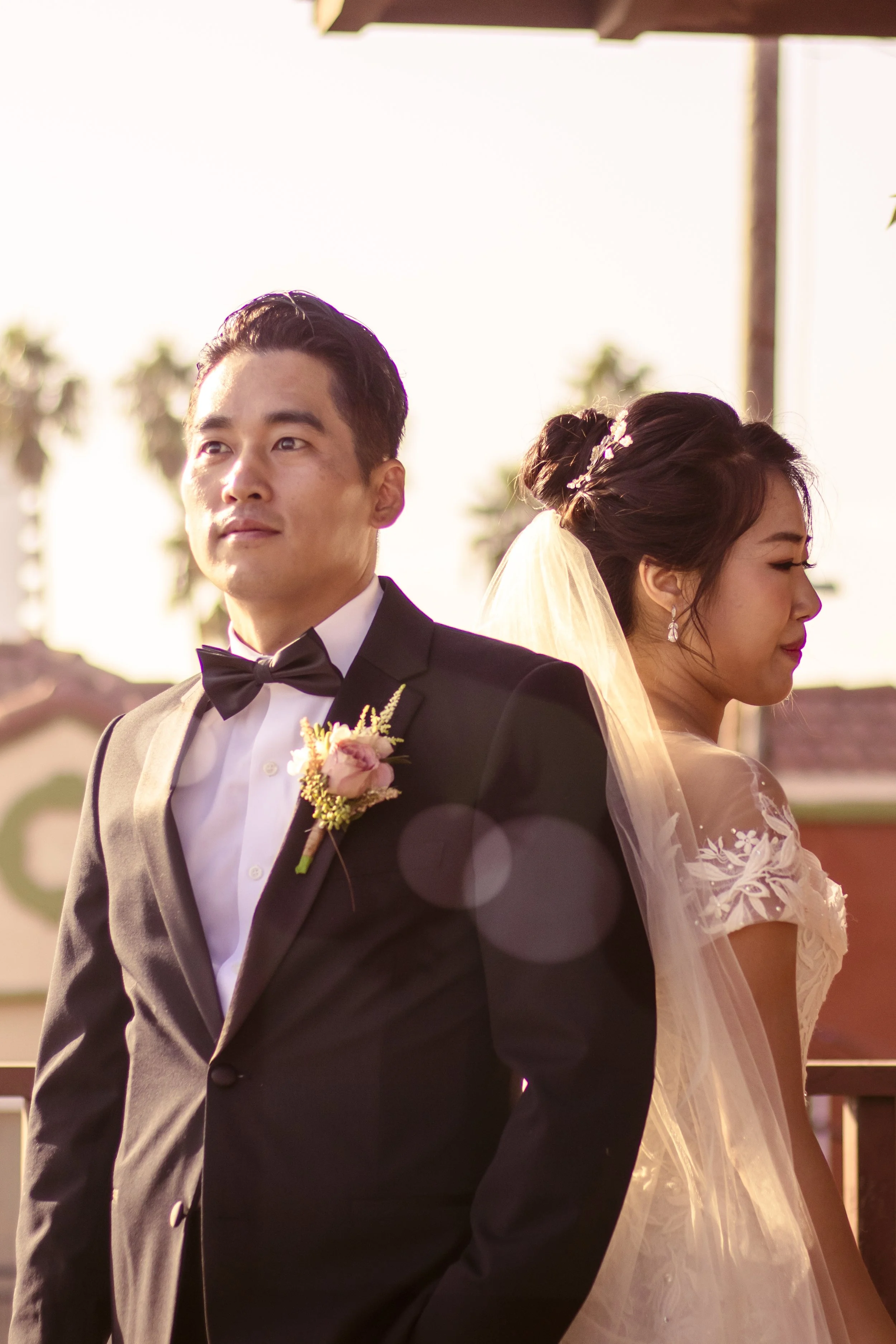 Bride and groom standing back-to-back, outdoor wedding setting.