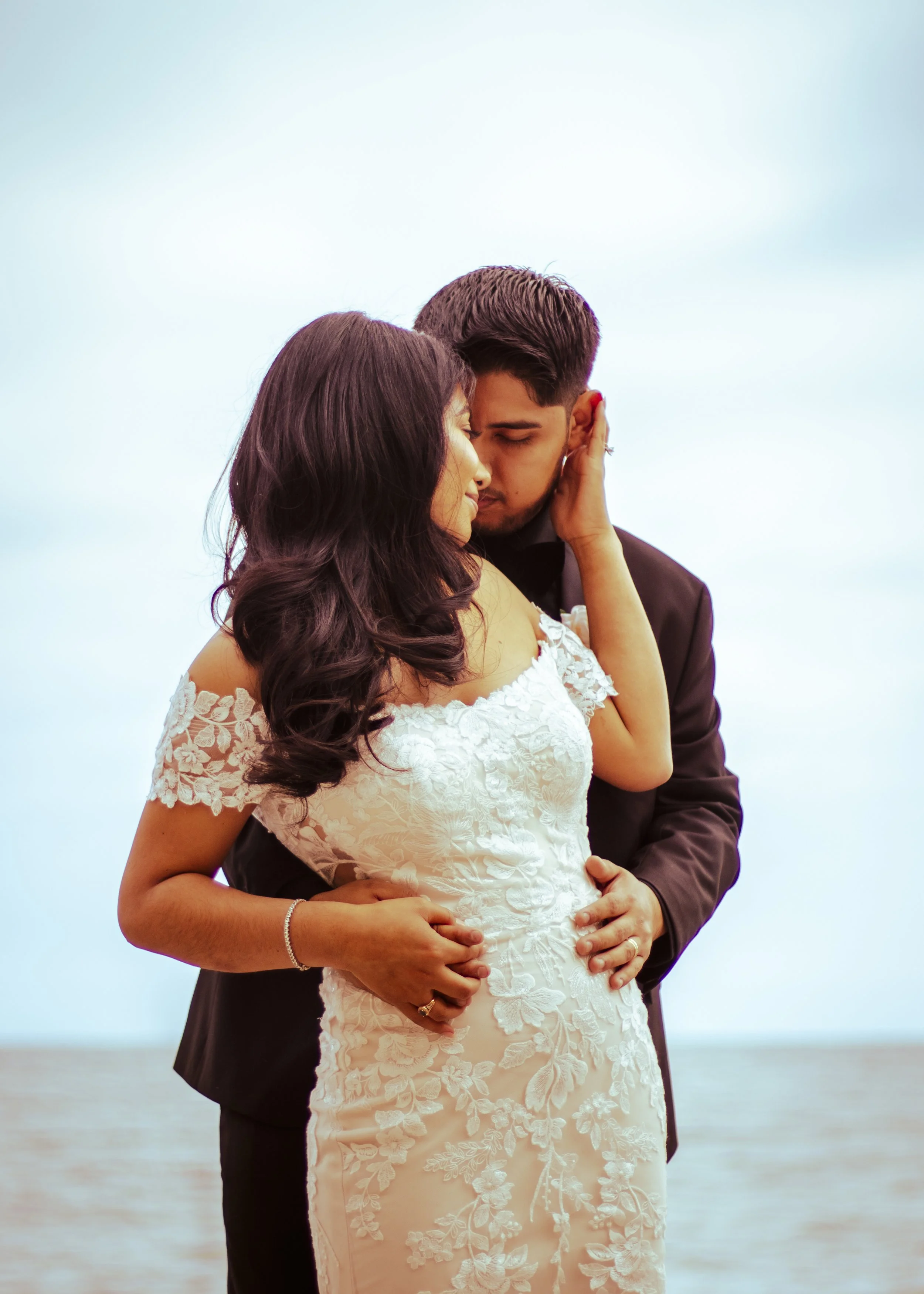 Bride and groom embracing on a beach.
