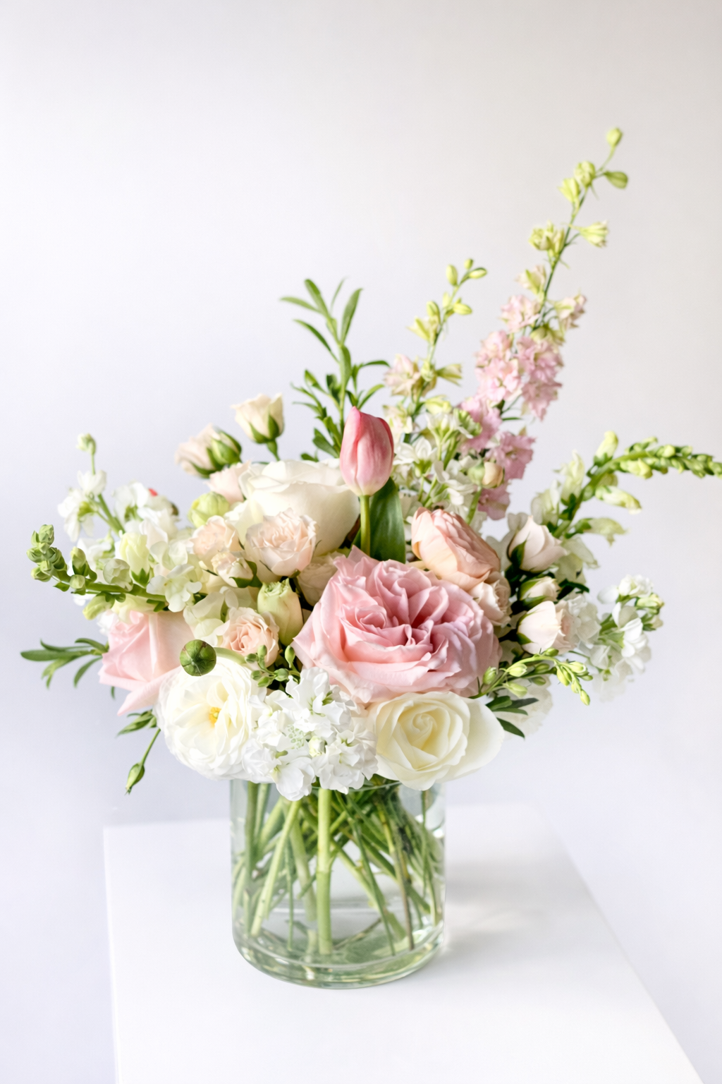 Soft pink floral elegance in glass vase.png