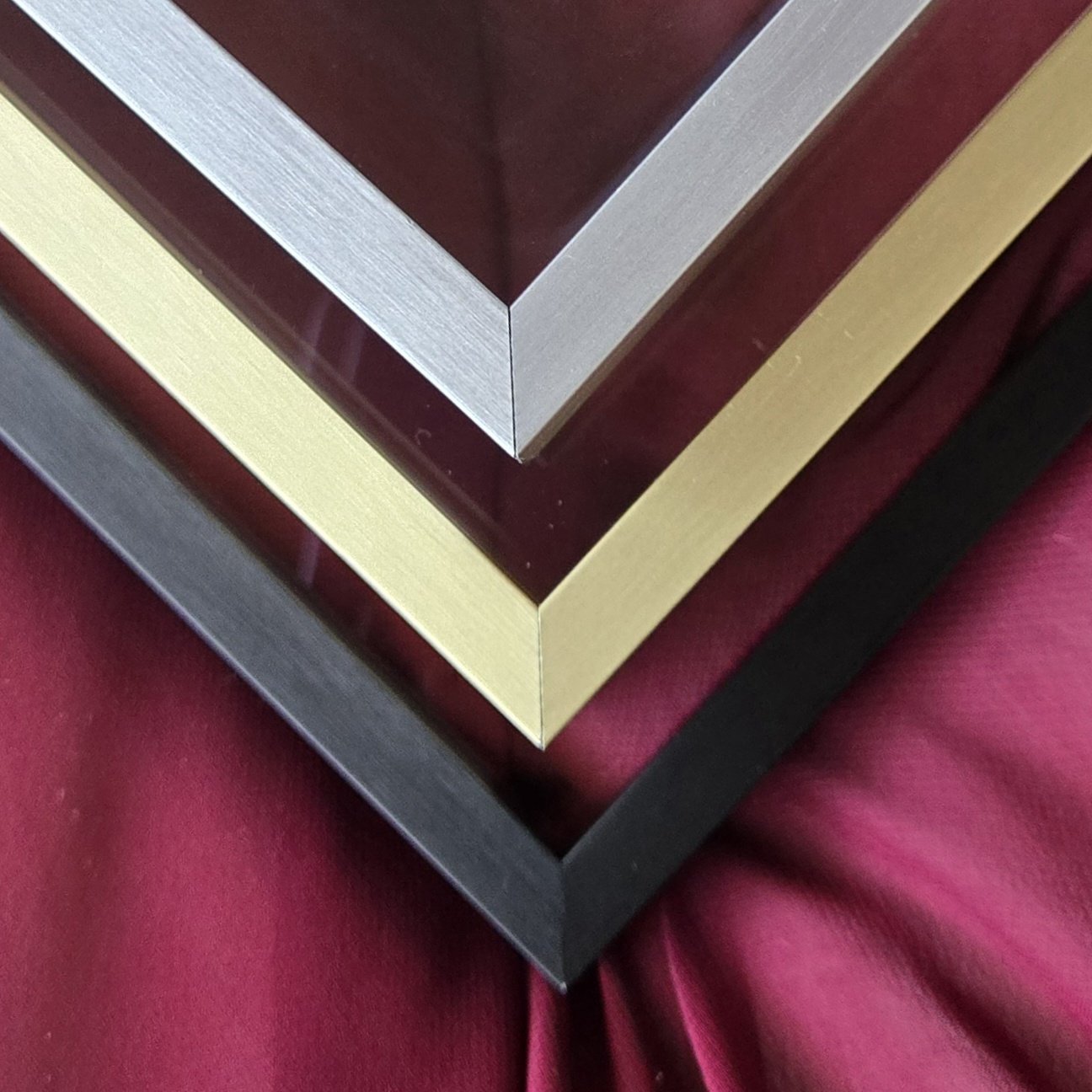 Close-up of a layered metal picture frame with different shades of wood, resting on a white textured surface.
