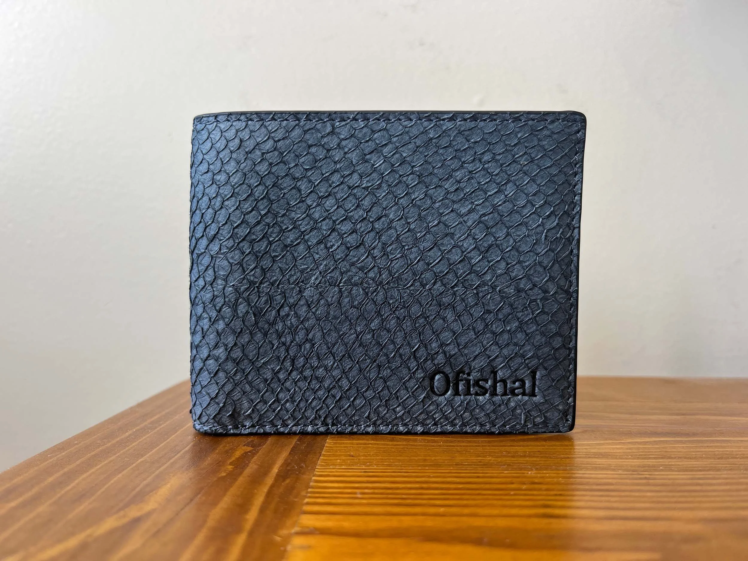 Ofishal wallet in ocean blue resting on a nightstand