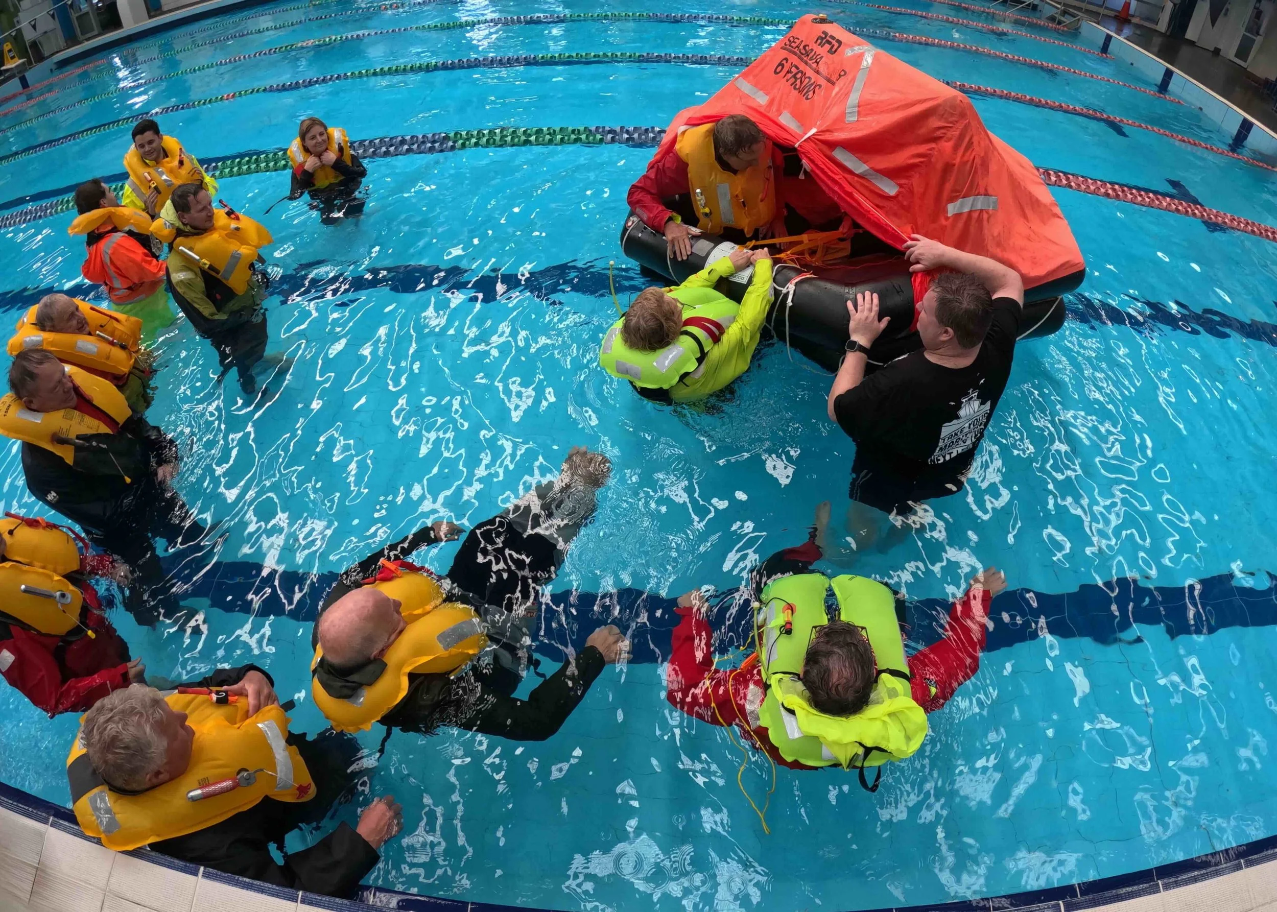 Sailors practicing getting into the liferaft in the pool