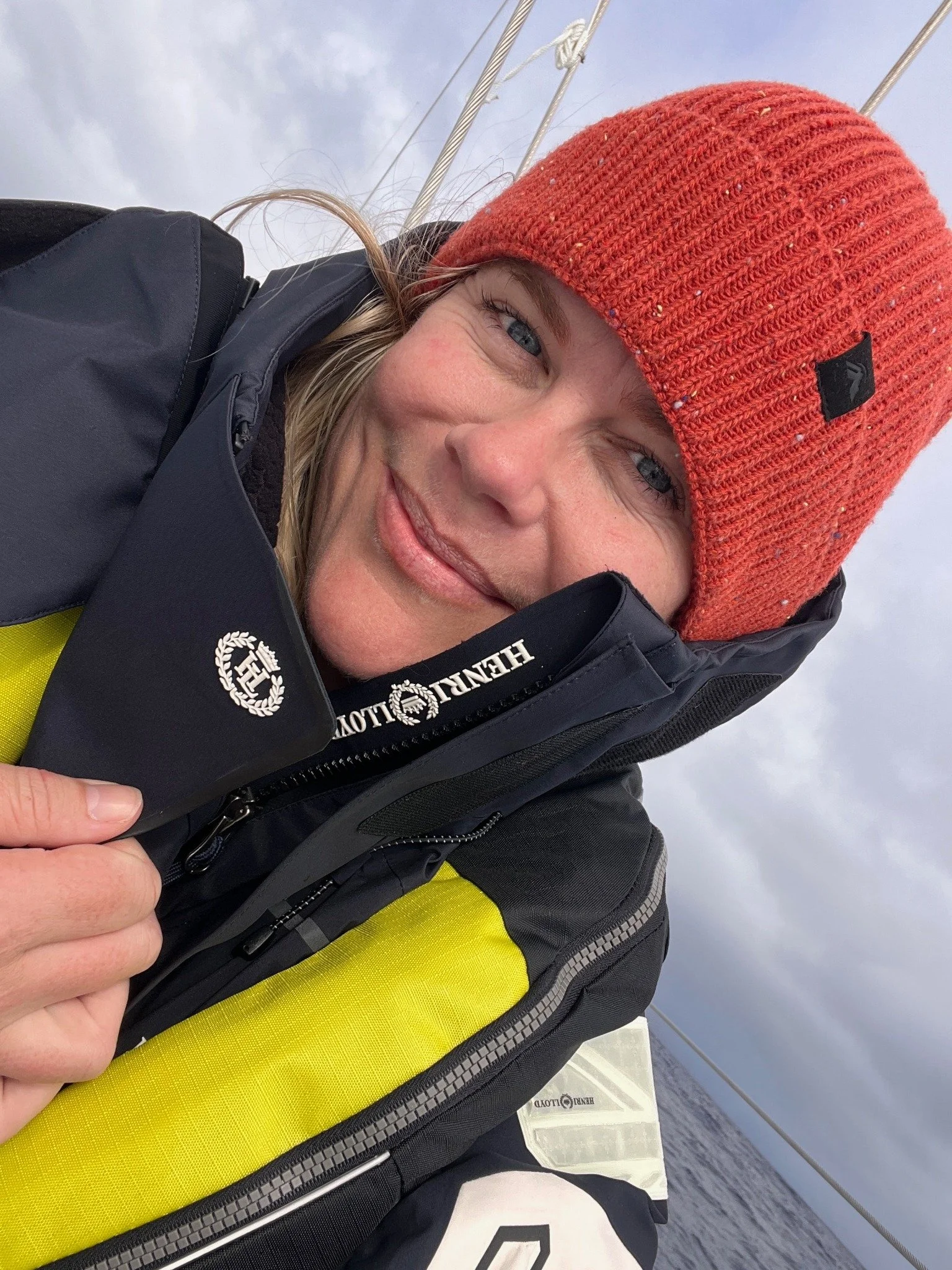 Tara Cooney aboard a yacht wearing an orange knitted beanie and sailing jacket.