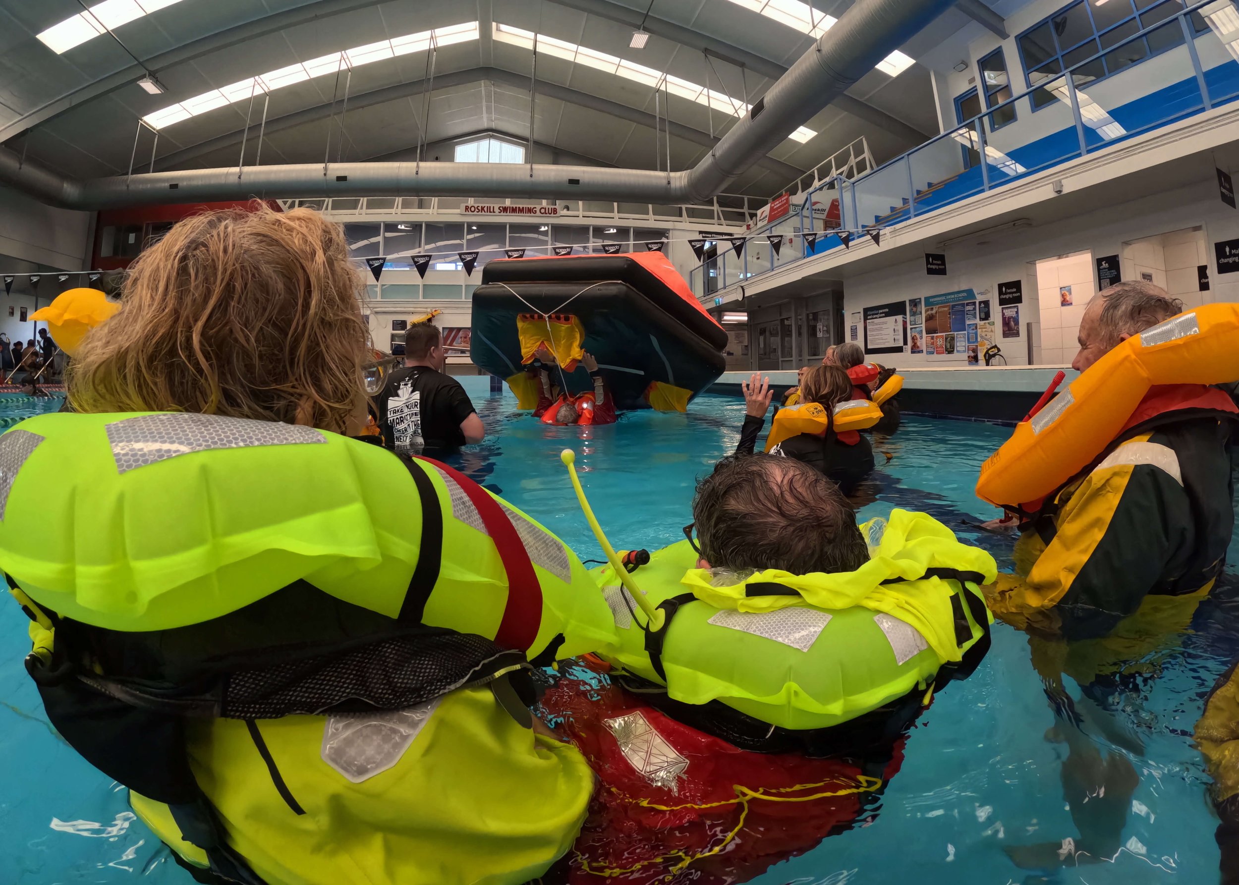Sailors in a pool practicing righting a liferaft