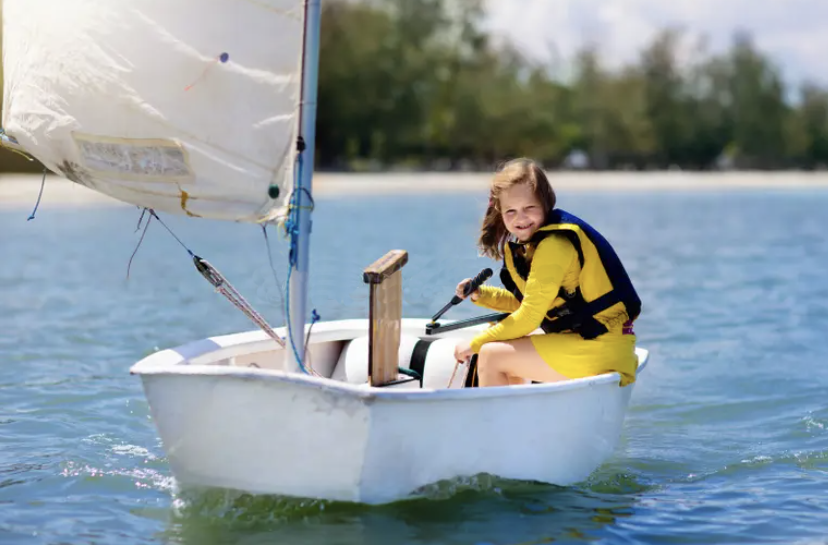 Young girl sailing in an optimist dinghy