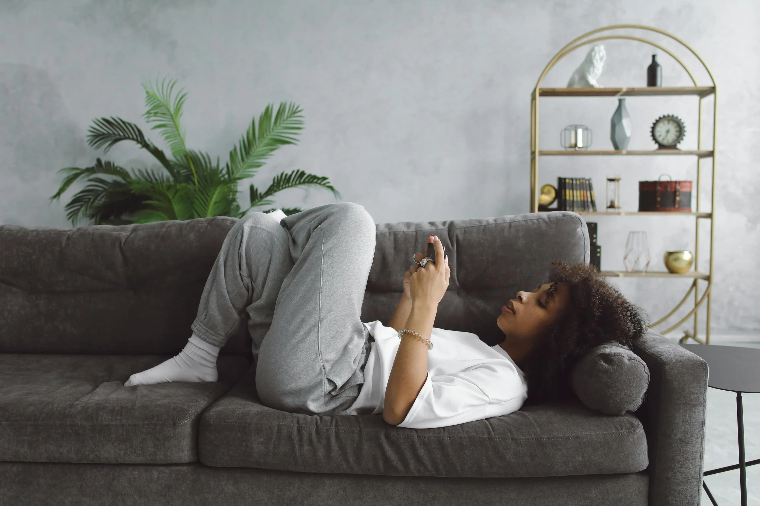 young woman with curly hair laying on couch