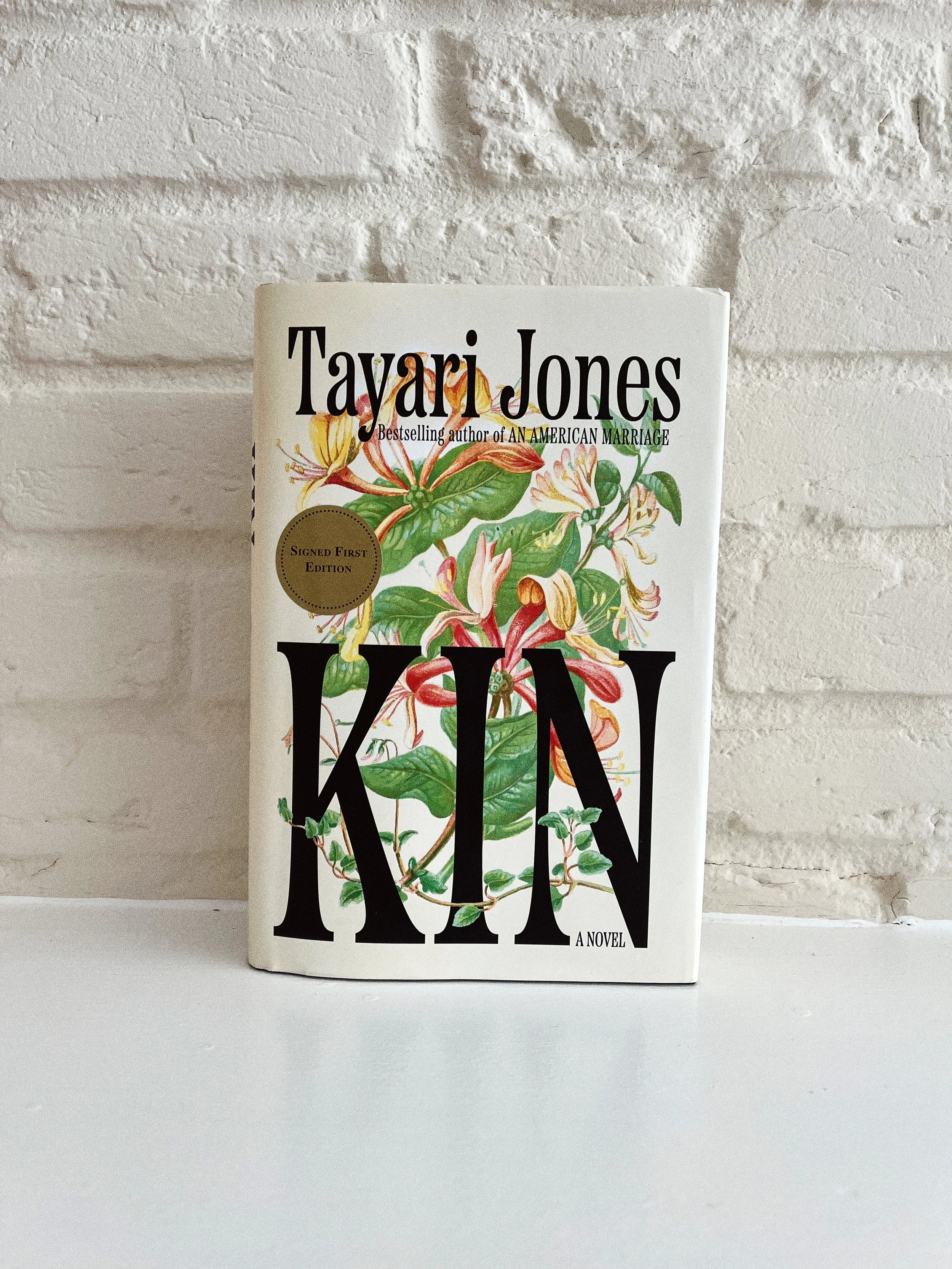 Kin by Tayari Jones against a white brick wall