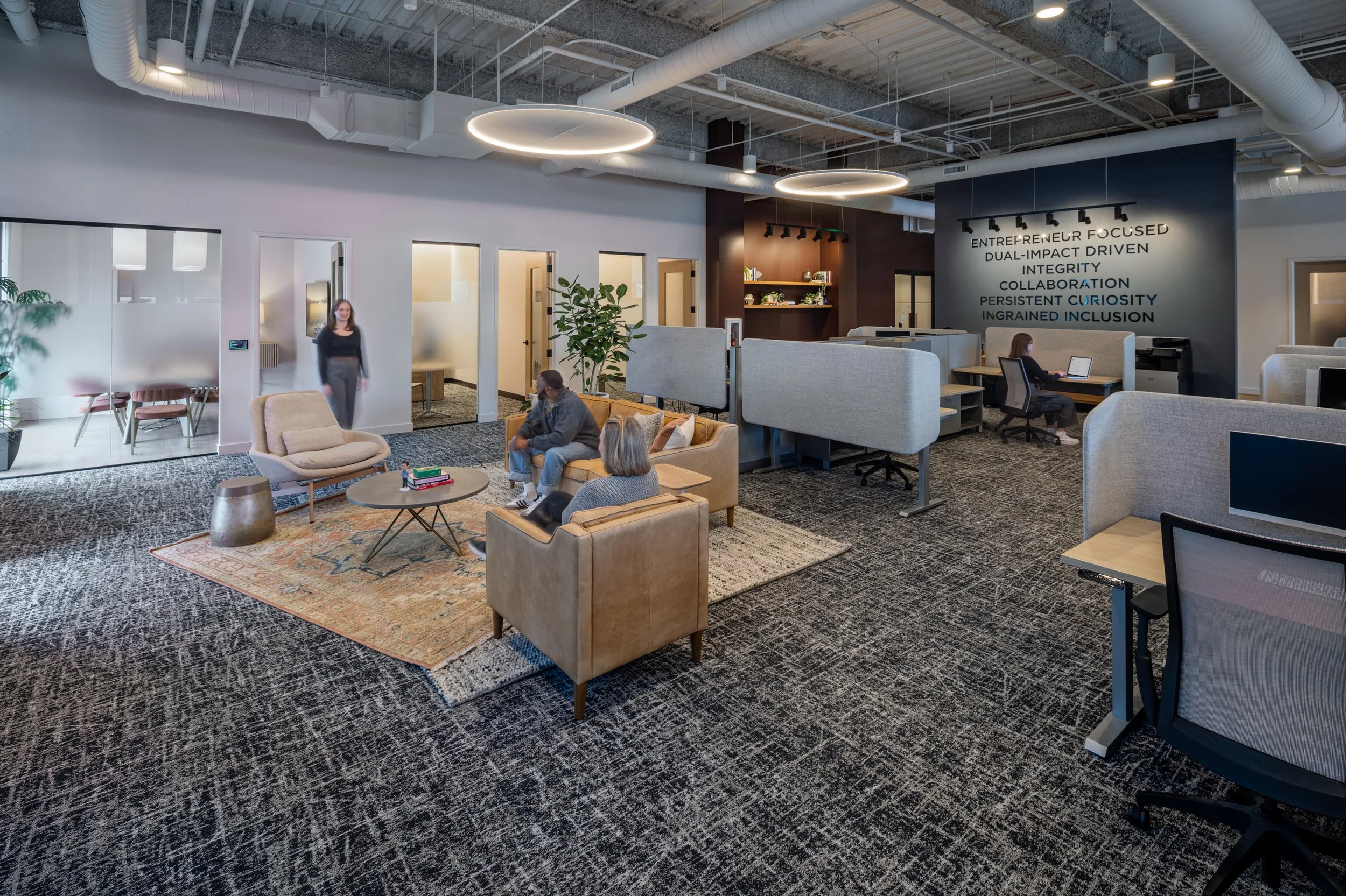 Modern office lobby with seating area, people working on laptops, and decor.