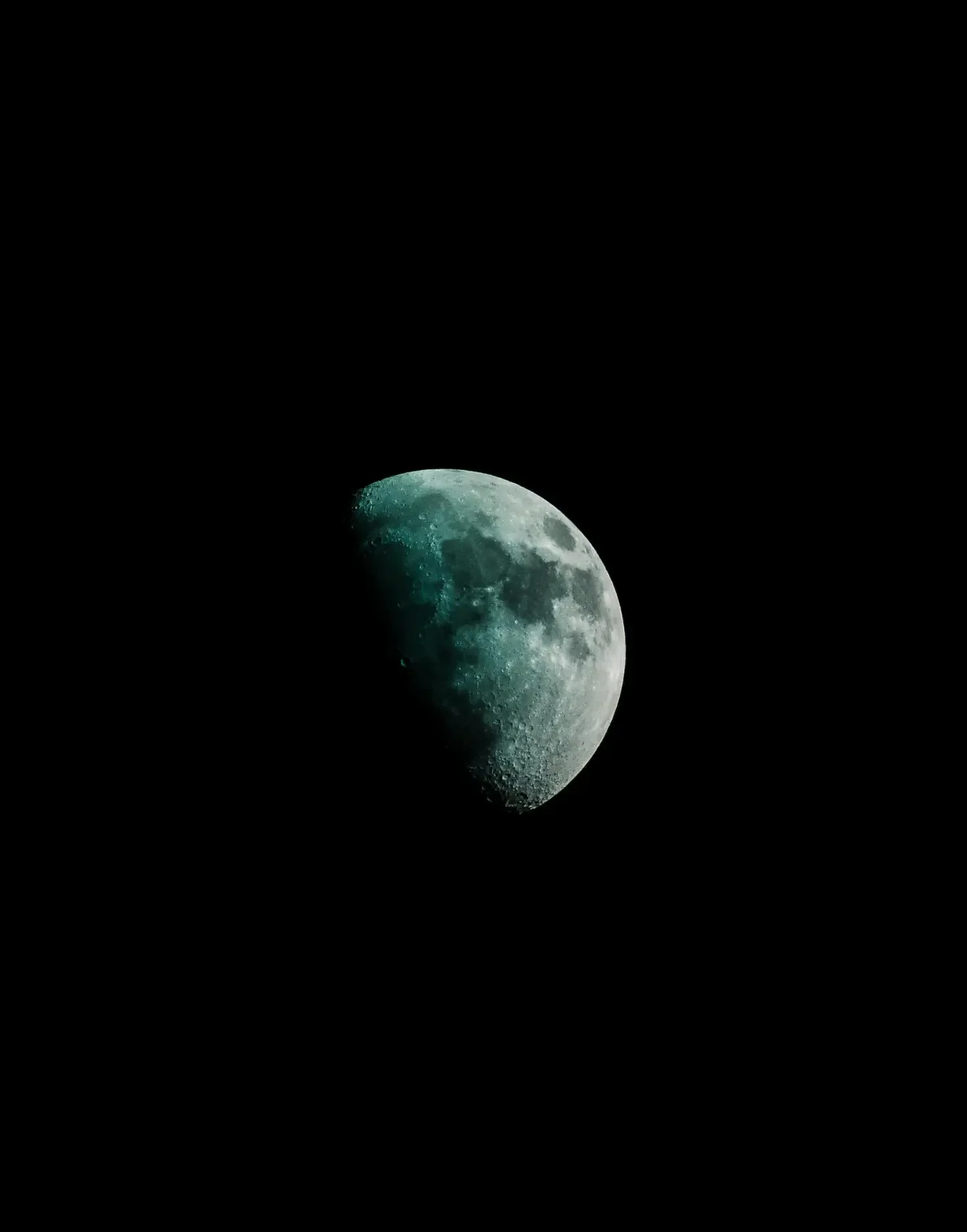 The moon partially illuminated against a dark sky.