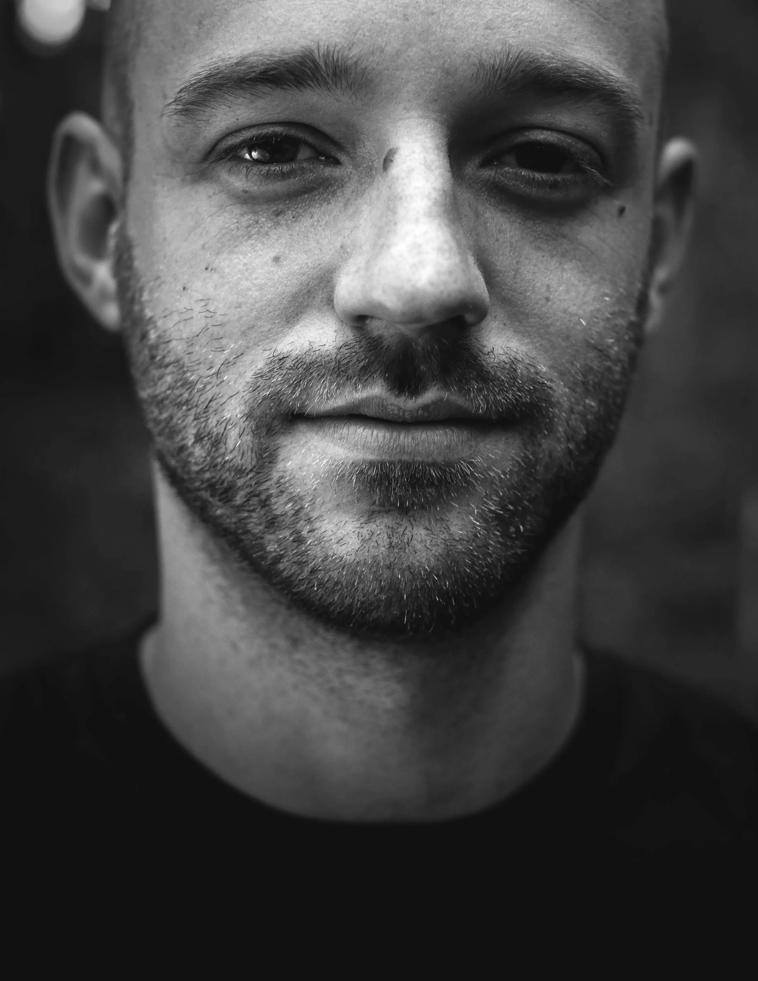 Black and white close-up portrait of a man with a beard and short hair.