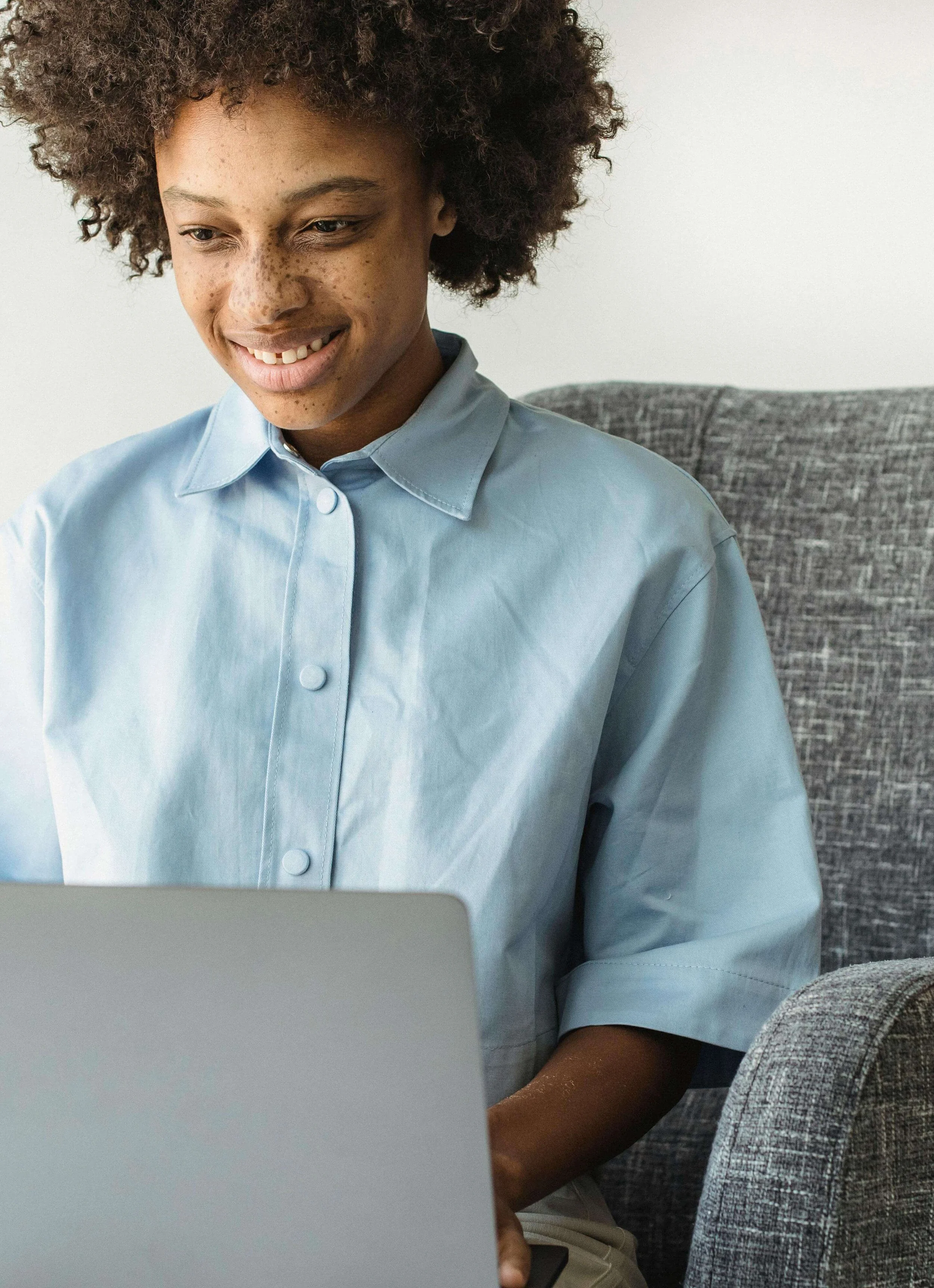 Teen sitting on a couch using a laptop in a comfortable home setting. Teen therapy in Lee’s Summit, MO supports teens from professional families by offering flexible options that fit into busy schedules and home routines.